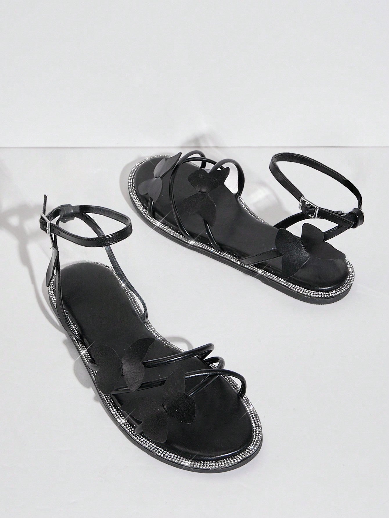 Women's flat open-toe sandals featuring a buckle detail and PU leather construction with a flat sole.