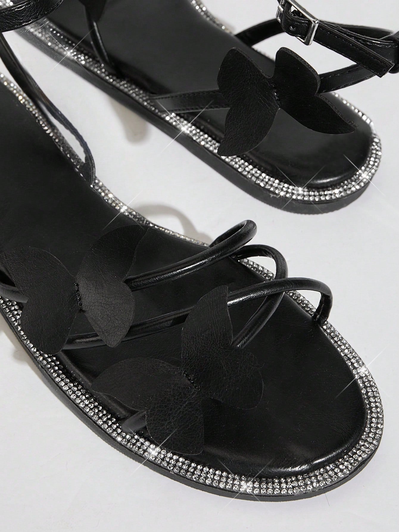 Women's flat open-toe sandals featuring a buckle detail and PU leather construction with a flat sole.