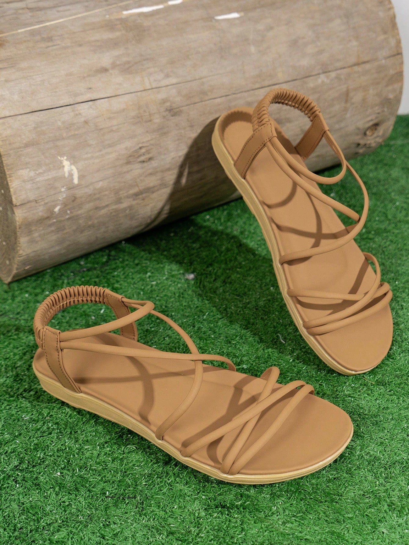 Women's beige flat sandals with criss cross straps, ankle strap, and open toe.