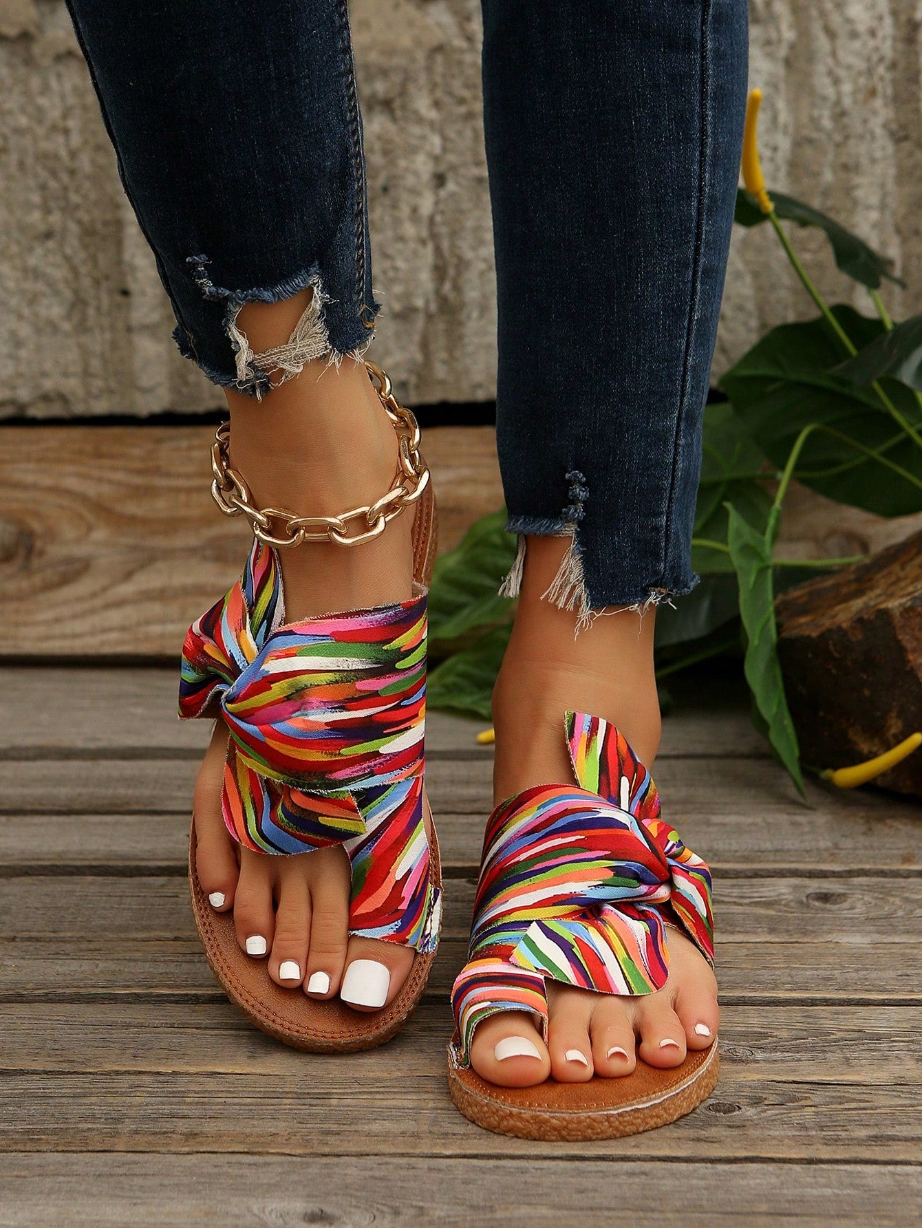 Women's flat slide sandals with bow tie, knot, and braided details, toe post design, and bohemian plant pattern.