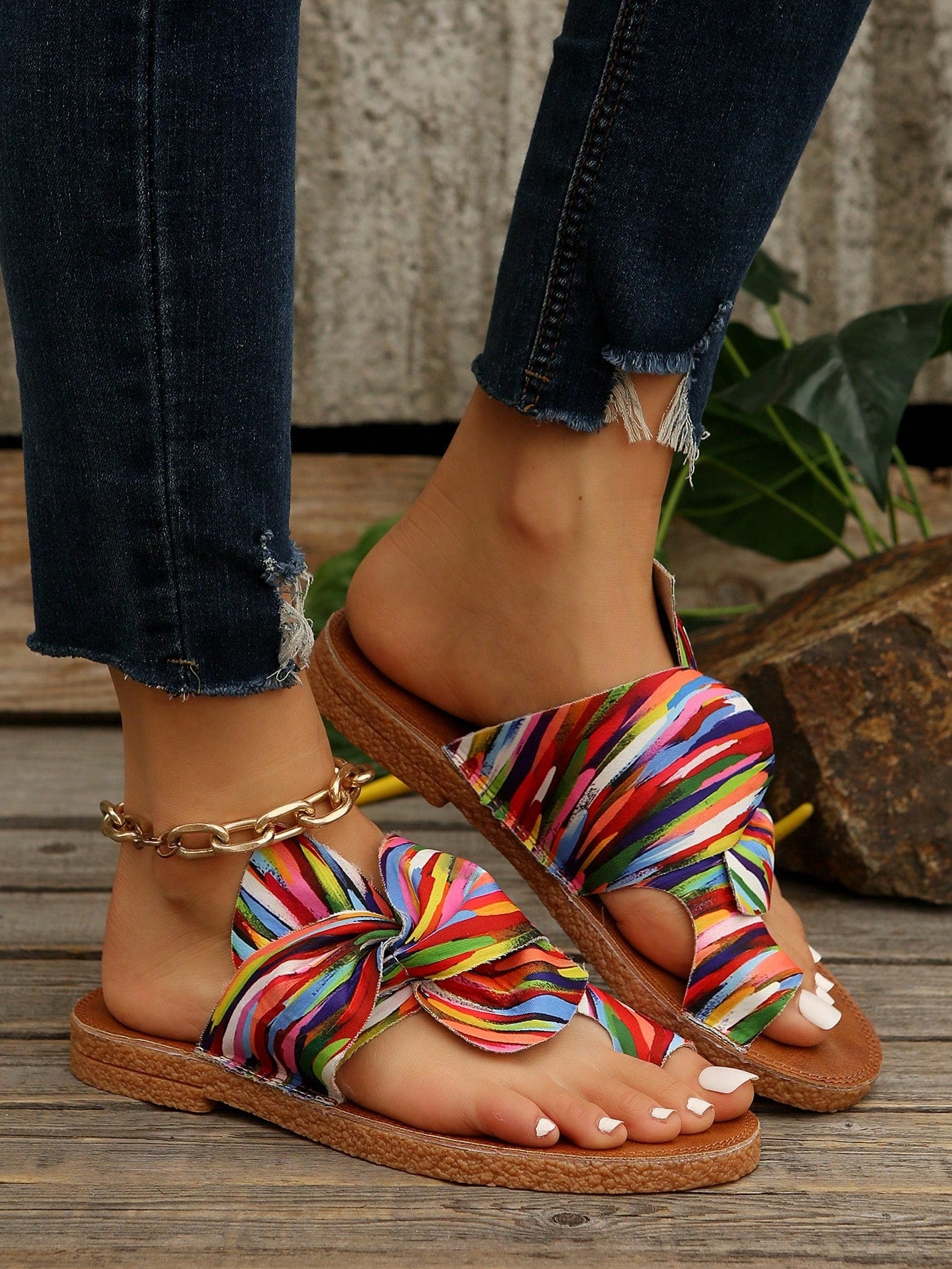 Women's flat slide sandals with bow tie, knot, and braided details, toe post design, and bohemian plant pattern.