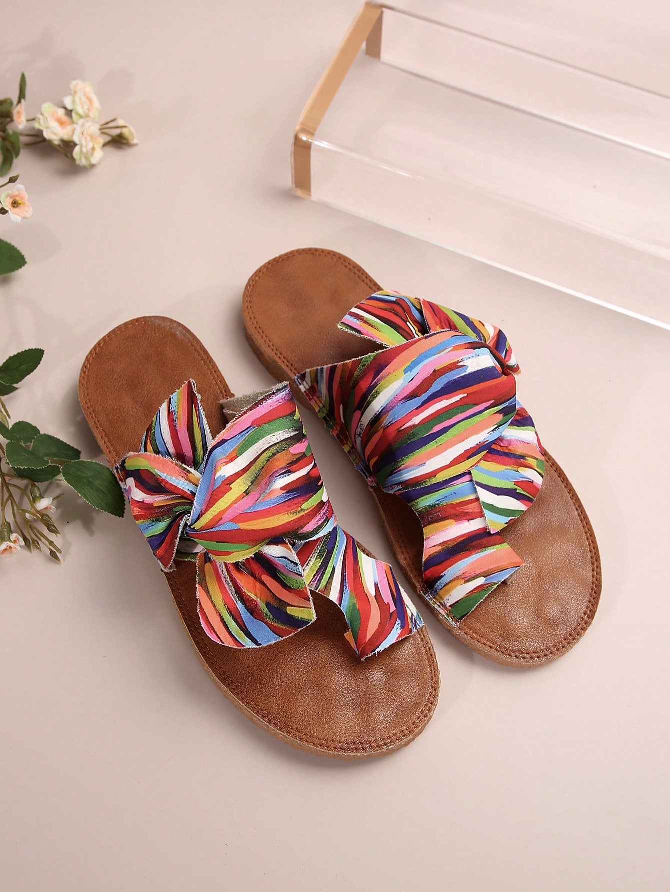 Women's flat slide sandals with bow tie, knot, and braided details, toe post design, and bohemian plant pattern.