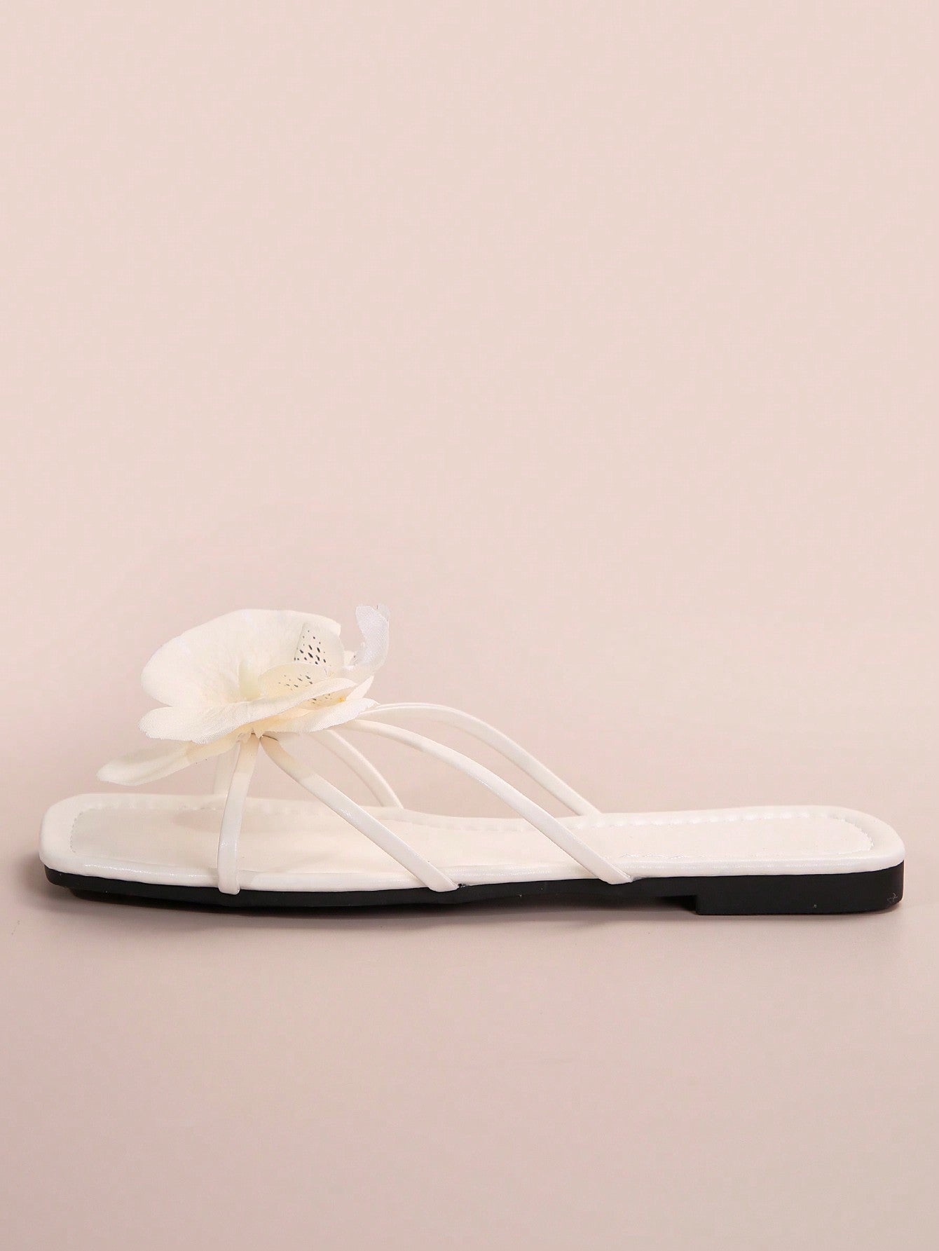 Women's flat slide sandals with open toe, floral applique detail, and criss-cross straps, shown as casual vacation-style summer footwear.