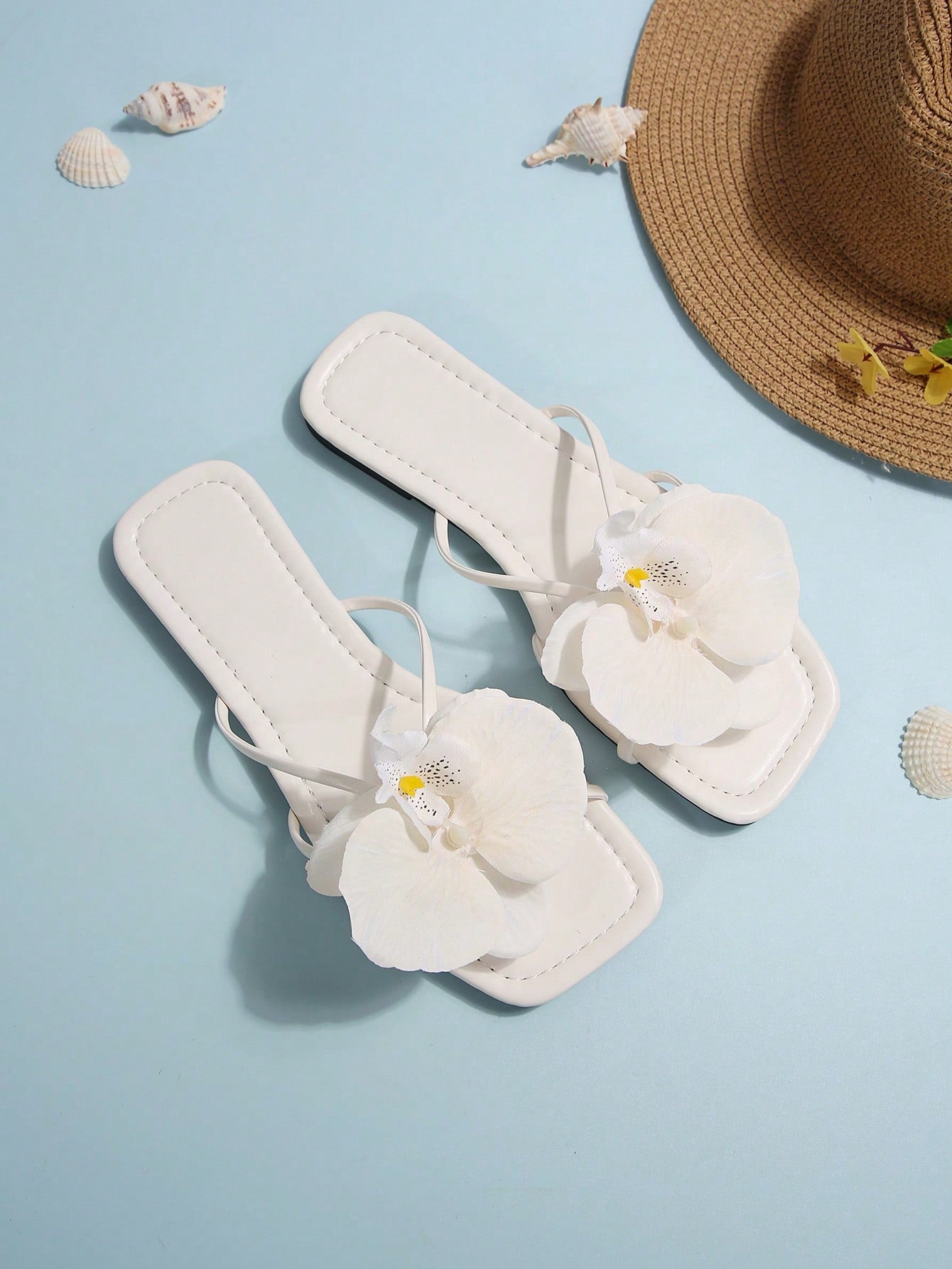 Women's flat slide sandals with open toe, floral applique detail, and criss-cross straps, shown as casual vacation-style summer footwear.