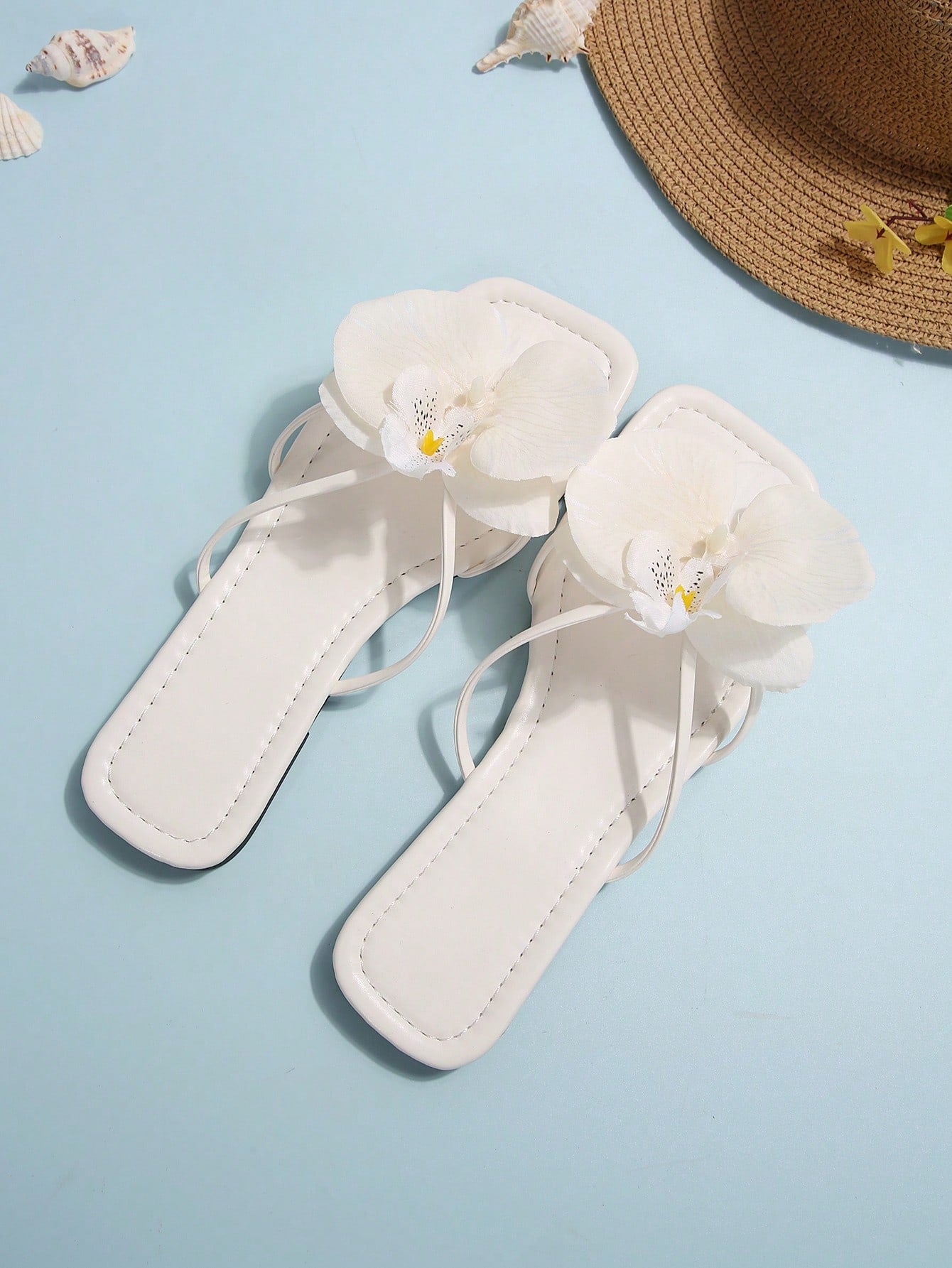 Women's flat slide sandals with open toe, floral applique detail, and criss-cross straps, shown as casual vacation-style summer footwear.