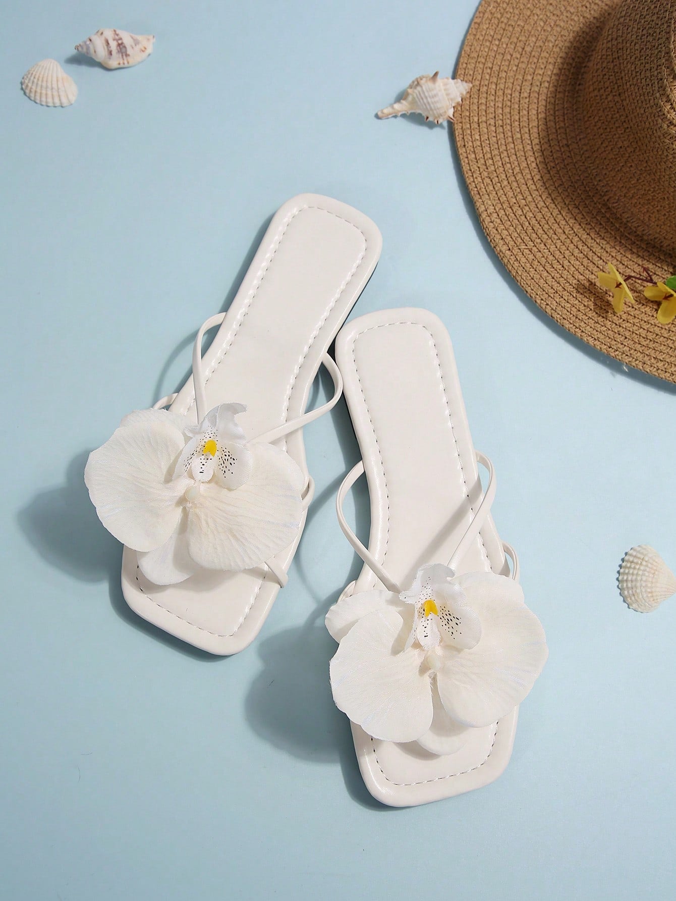 Women's flat slide sandals with open toe, floral applique detail, and criss-cross straps, shown as casual vacation-style summer footwear.