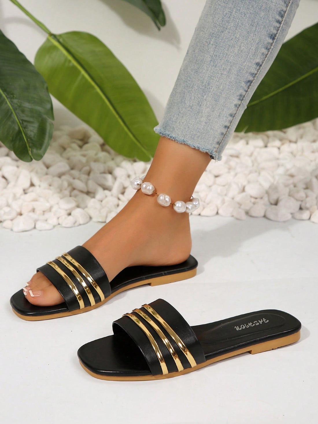 Women’s black flat slide sandals with open toe design and gold stripe decor on the upper