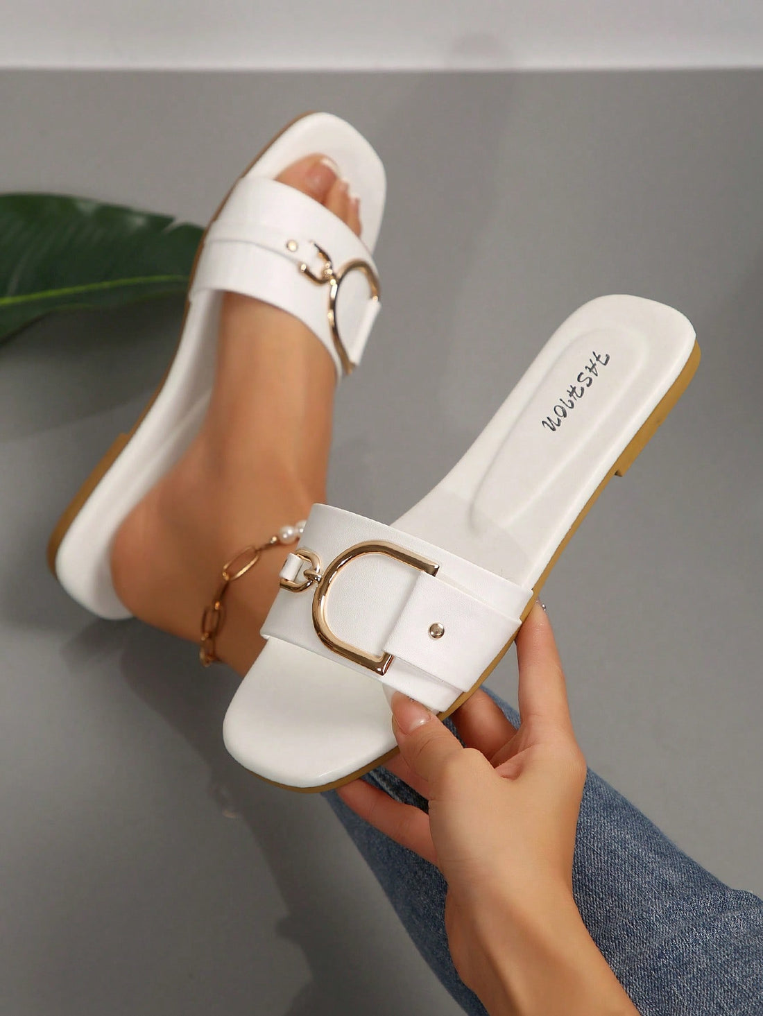 Pair of women’s wide fit flat slide sandals with an open toe, slip-on style, plain design, and gold buckle detail.