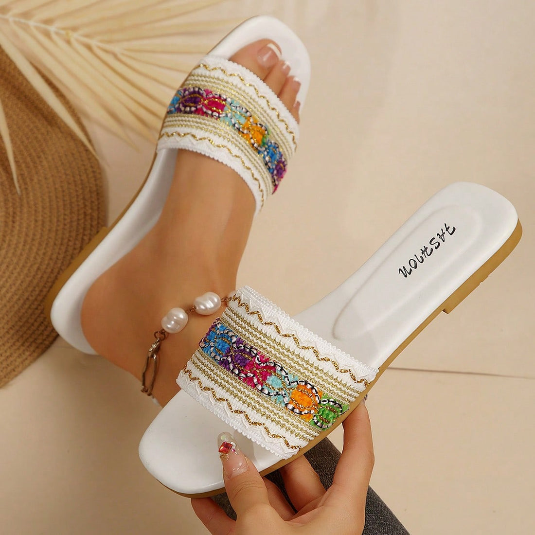 Women's white open-toe flat slide slippers with asymmetrical buckle strap, lace, sequin, and glitter detailing, suitable for indoor home use and outdoor wear.