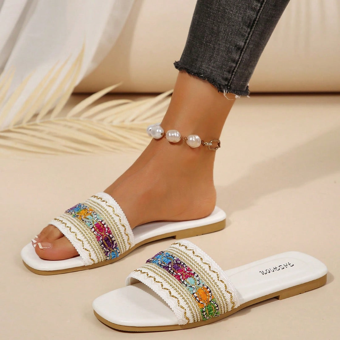 Women's white open-toe flat slide slippers with asymmetrical buckle strap, lace, sequin, and glitter detailing, suitable for indoor home use and outdoor wear.