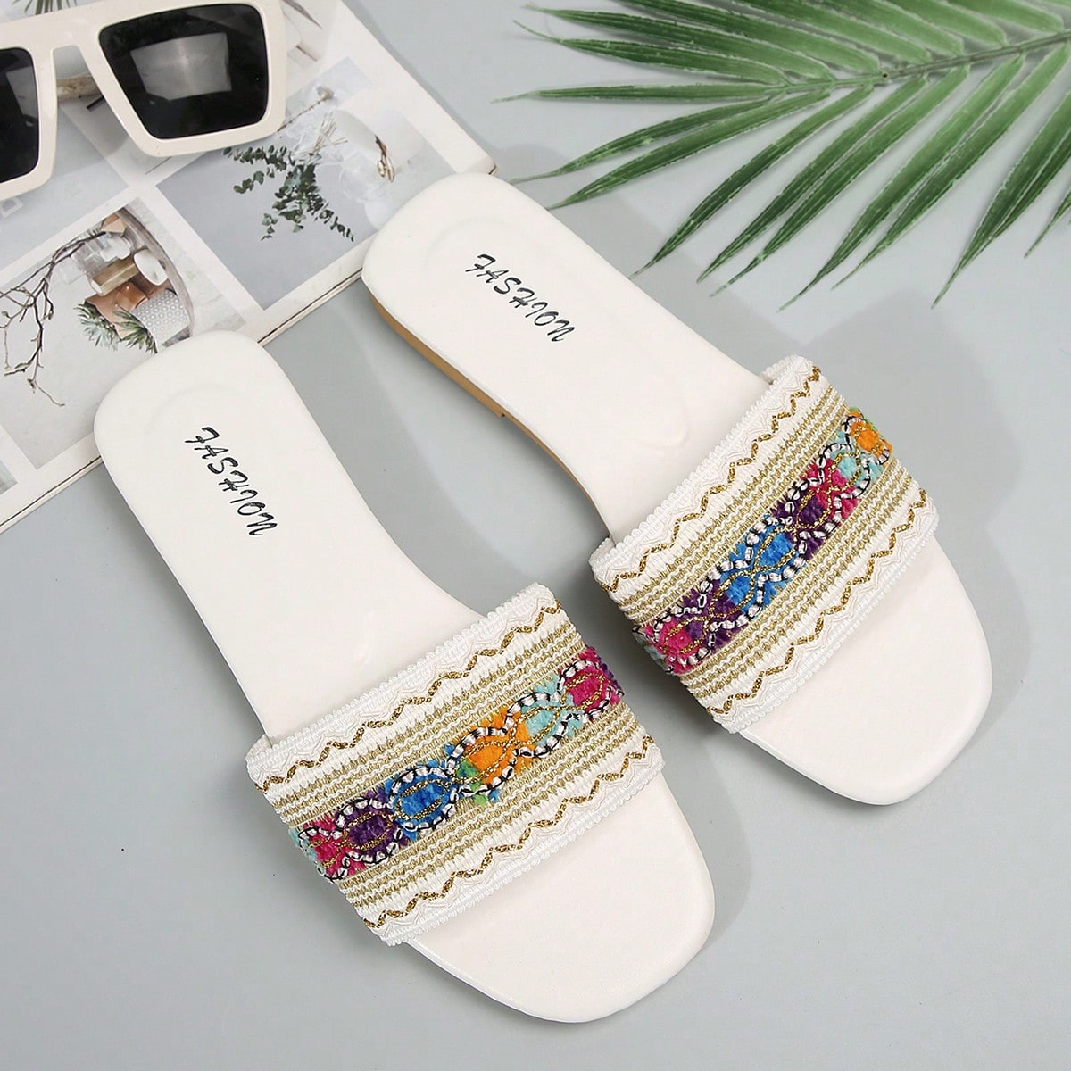 Women's white open-toe flat slide slippers with asymmetrical buckle strap, lace, sequin, and glitter detailing, suitable for indoor home use and outdoor wear.