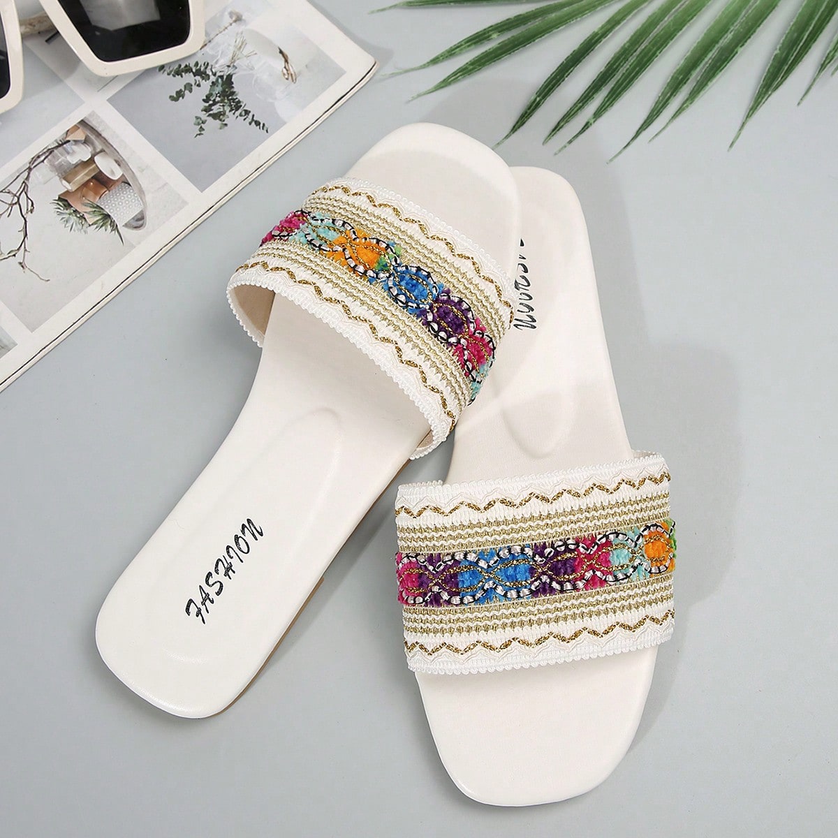Women's white open-toe flat slide slippers with asymmetrical buckle strap, lace, sequin, and glitter detailing, suitable for indoor home use and outdoor wear.