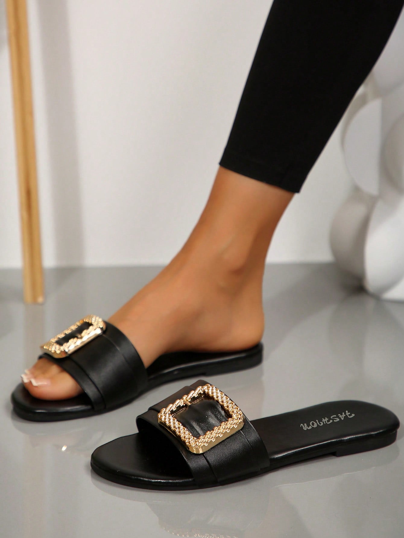 Pair of women's black flat slide sandals featuring rhinestone embellishments, metal accents, and a gold-strip detail on the upper, with an open-toe slip-on design.