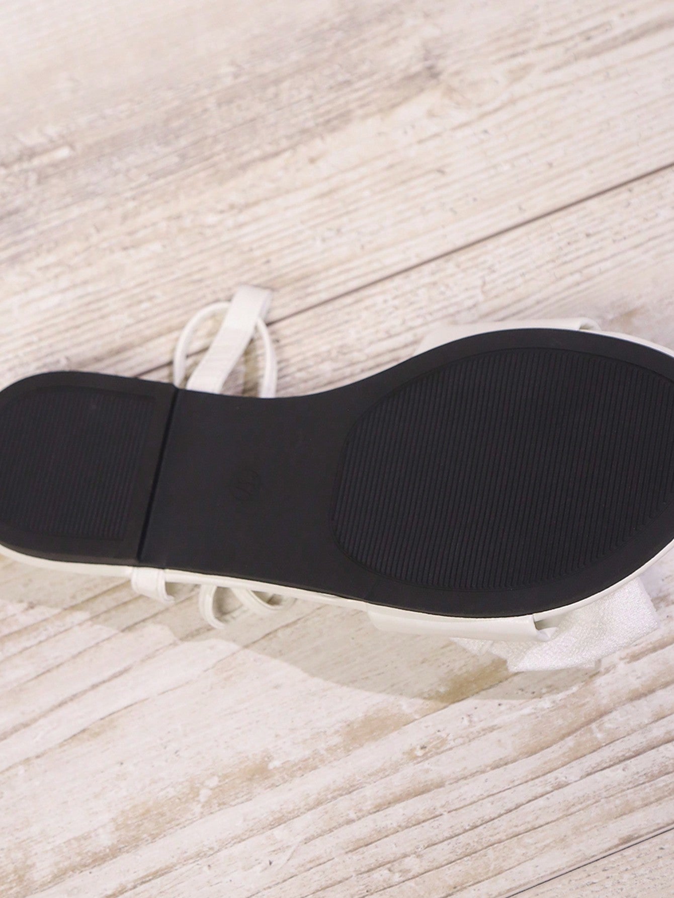 Women's flat strappy sandals with bow detail, open toe, and Roman-style criss-cross lace-up design in an elegant look.