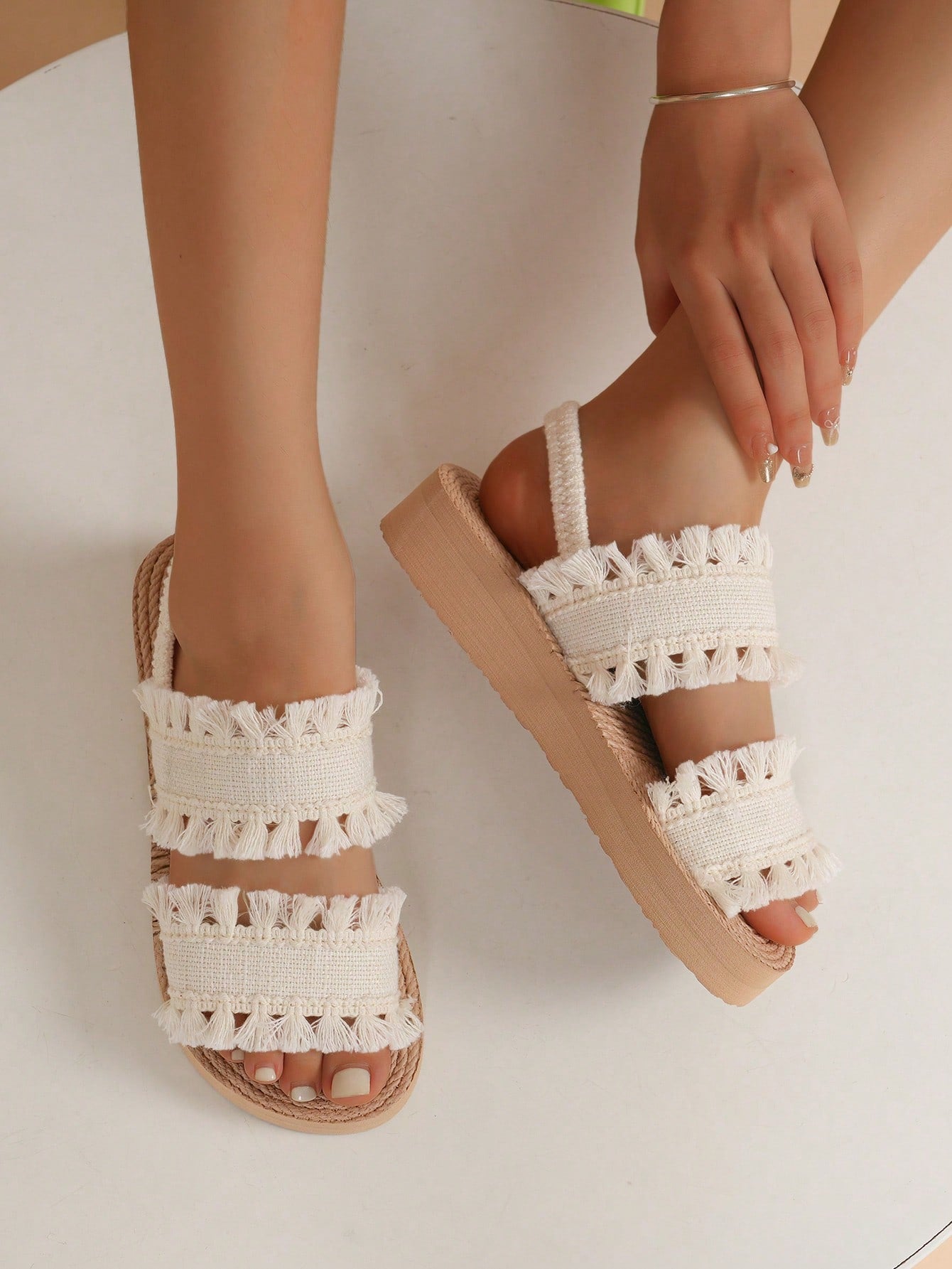 Women's open toe slip-on wedge sandals with criss cross straps and folk-custom styling, featuring raw hem, fringe, tassel, braid, and tape details.