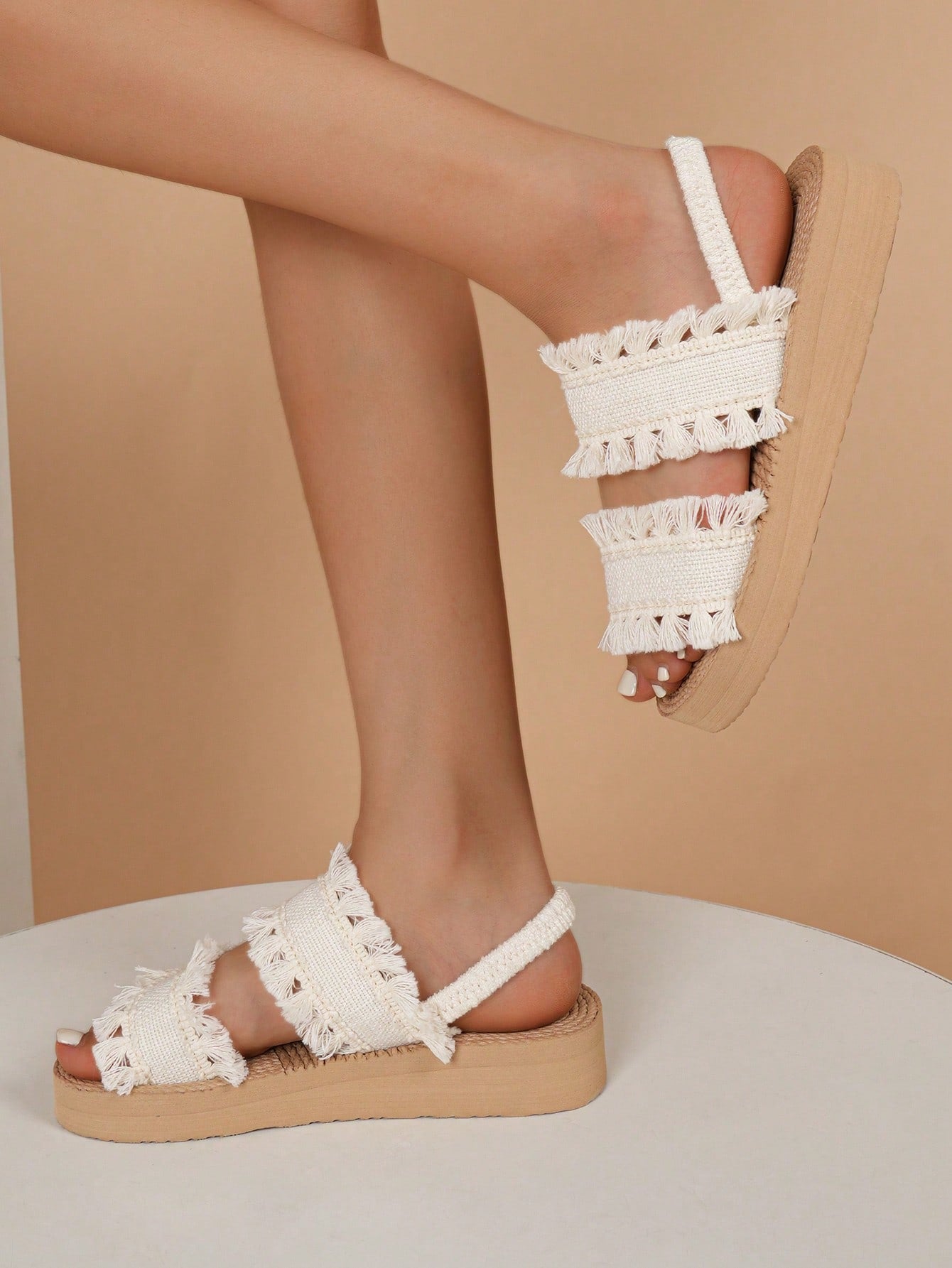 Women's open toe slip-on wedge sandals with criss cross straps and folk-custom styling, featuring raw hem, fringe, tassel, braid, and tape details.