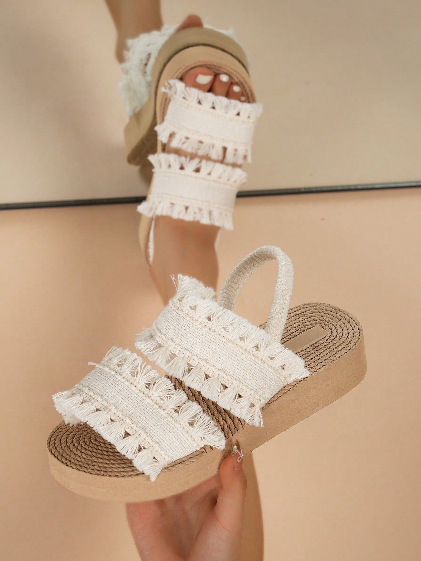 Women's open toe slip-on wedge sandals with criss cross straps and folk-custom styling, featuring raw hem, fringe, tassel, braid, and tape details.