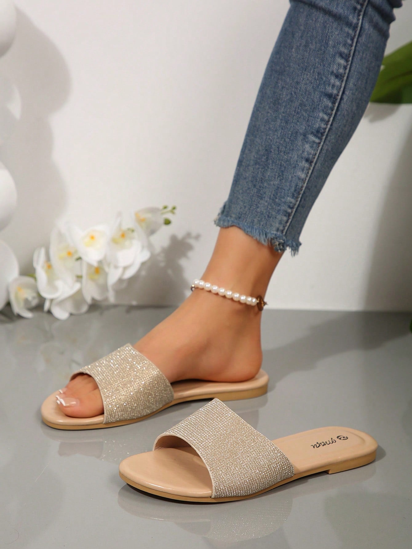 Pair of women's black flat slide sandals featuring rhinestone embellishments, metal accents, and a gold-strip detail on the upper, with an open-toe slip-on design.