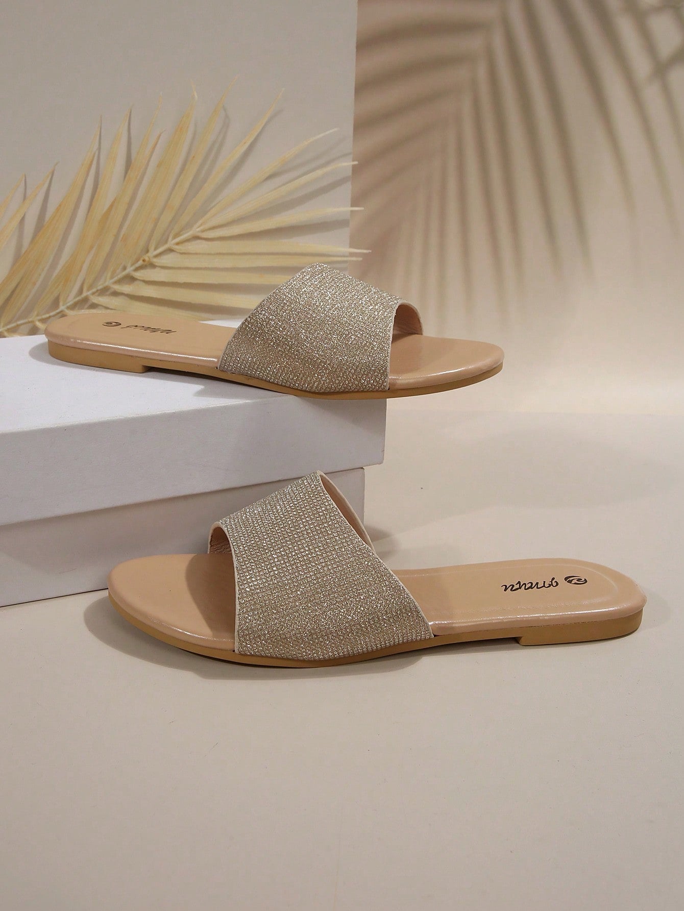 Pair of women's black flat slide sandals featuring rhinestone embellishments, metal accents, and a gold-strip detail on the upper, with an open-toe slip-on design.