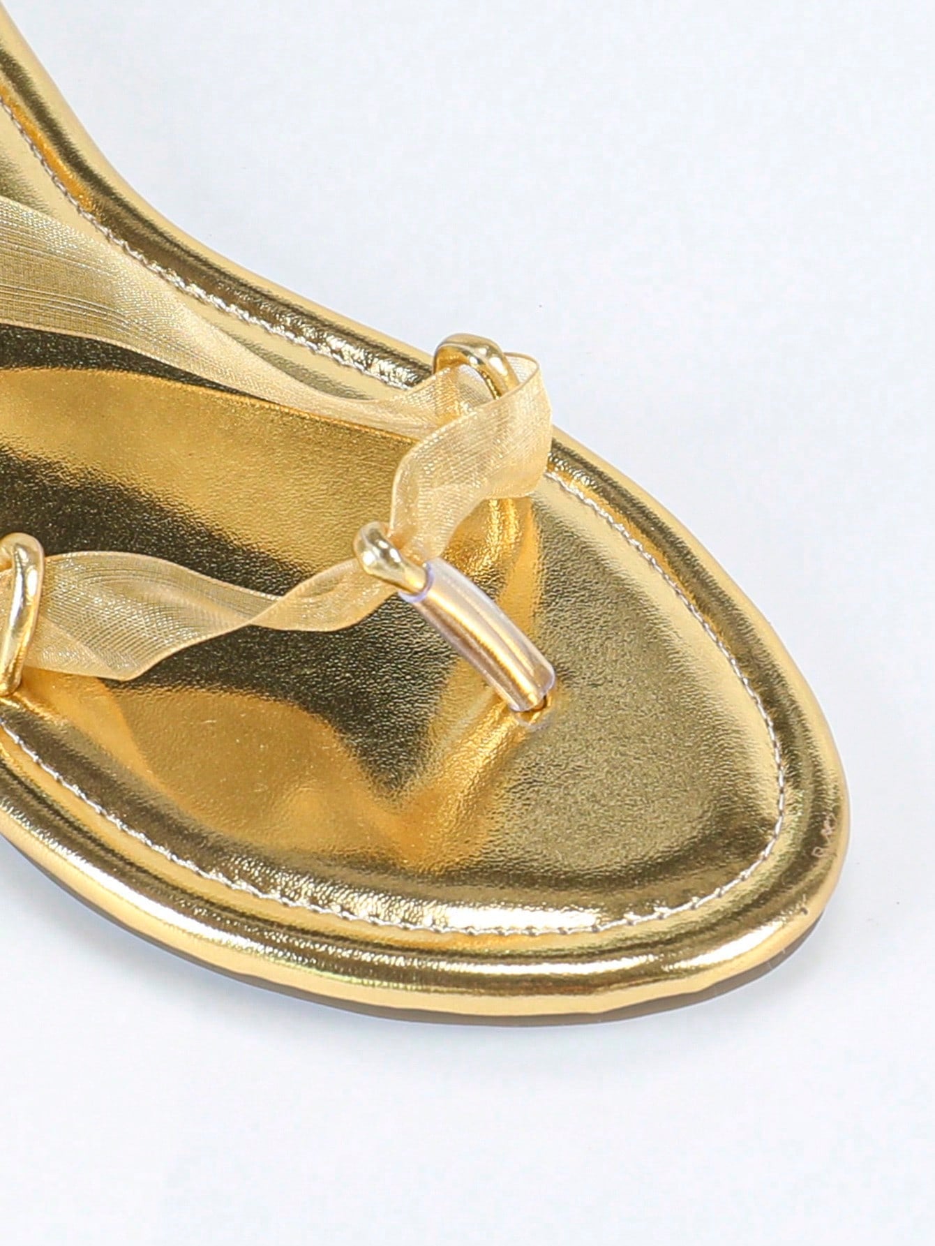 Women's gold flat sandals with metal accent detail, strappy lace-up design, and toe post thong style.