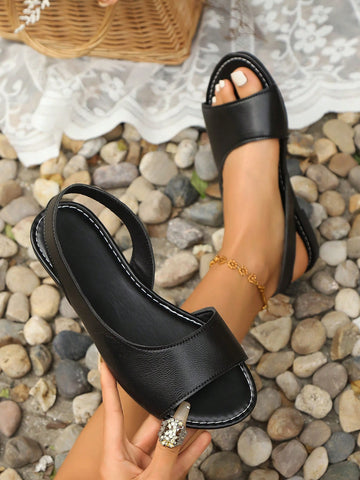 Women's black open-toe flat sandals with ankle strap and colorblock detail, casual beach and vacation style.