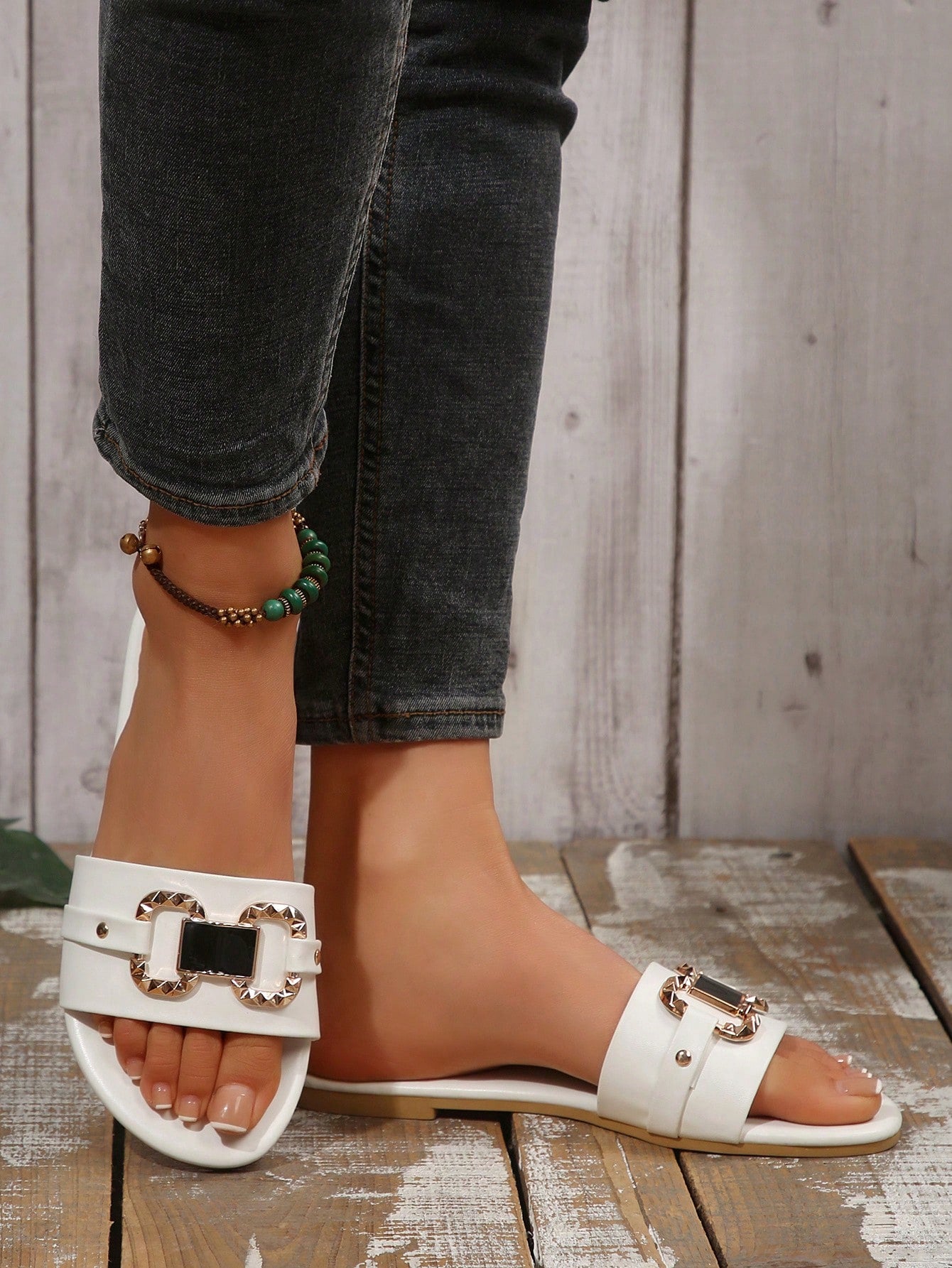Pair of women's black flat slide sandals featuring rhinestone embellishments, metal accents, and a gold-strip detail on the upper, with an open-toe slip-on design.