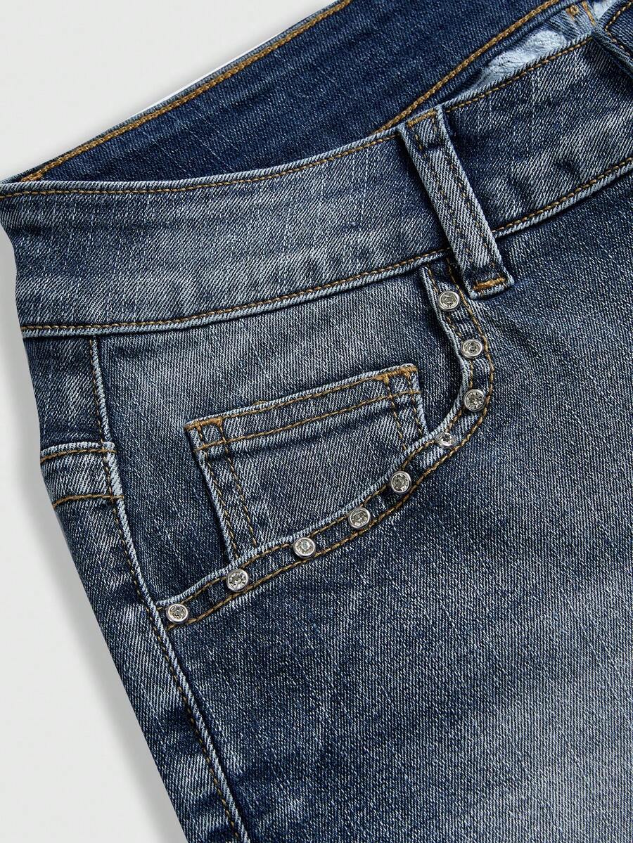 Blue ultra low waist mini shorts with ripped details, zipper fly, button closure, back wing embroidery, and rhinestone decor in a Y2K grunge punk style.