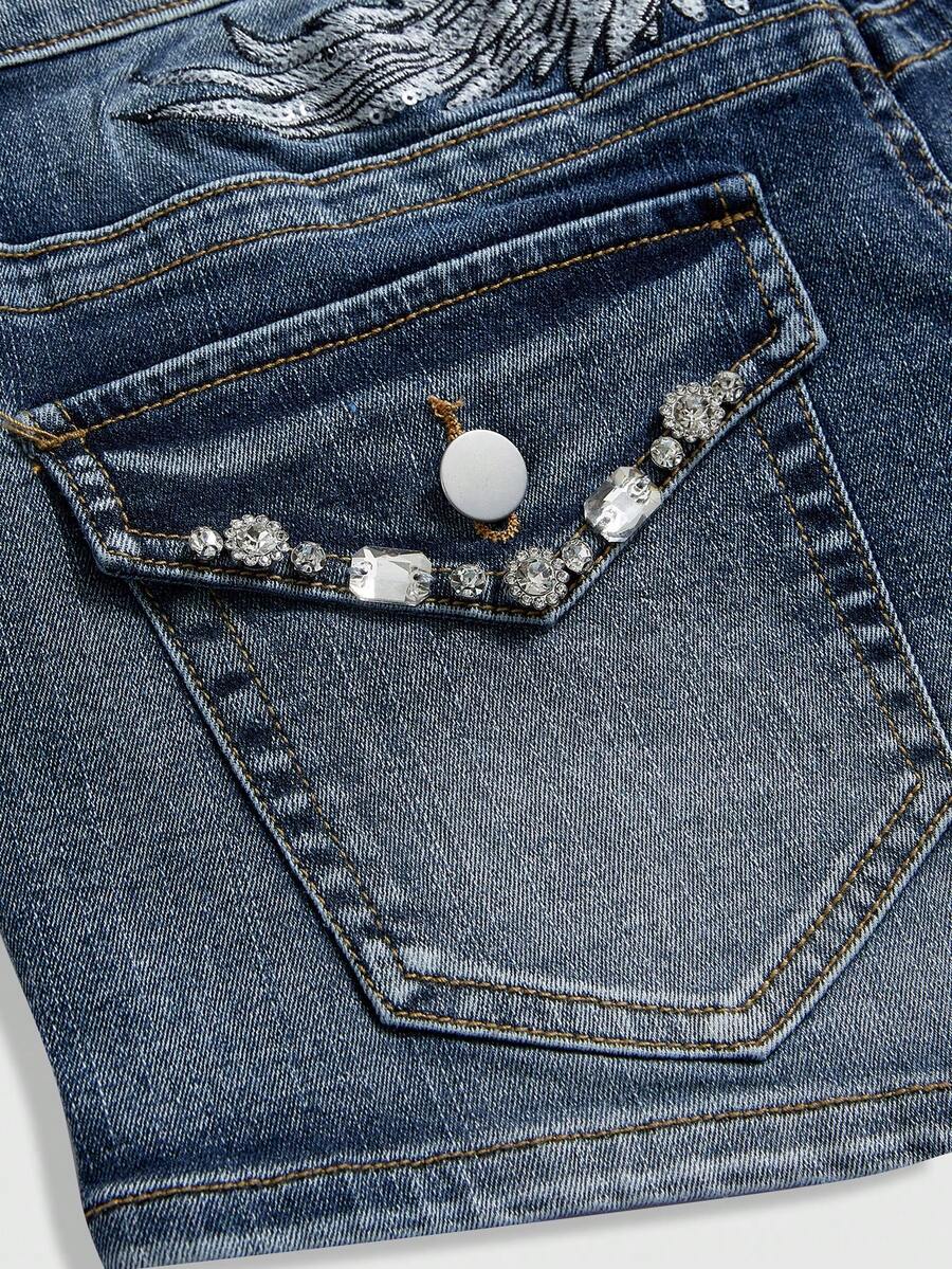 Blue ultra low waist mini shorts with ripped details, zipper fly, button closure, back wing embroidery, and rhinestone decor in a Y2K grunge punk style.