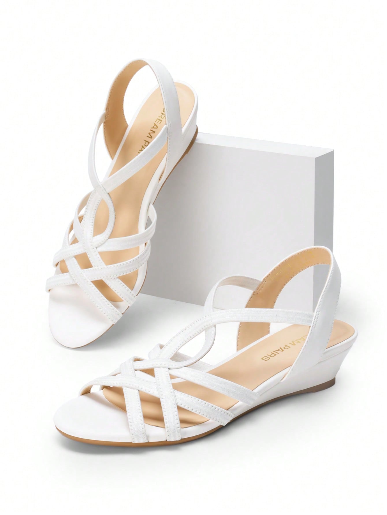 Women's open-toe low wedge sandals featuring crisscross straps, slingback ankle strap, and a classic wedge heel for dressy and everyday summer outfits.