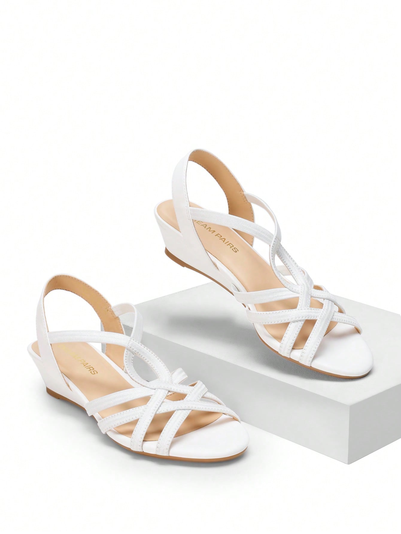 Women's open-toe low wedge sandals featuring crisscross straps, slingback ankle strap, and a classic wedge heel for dressy and everyday summer outfits.