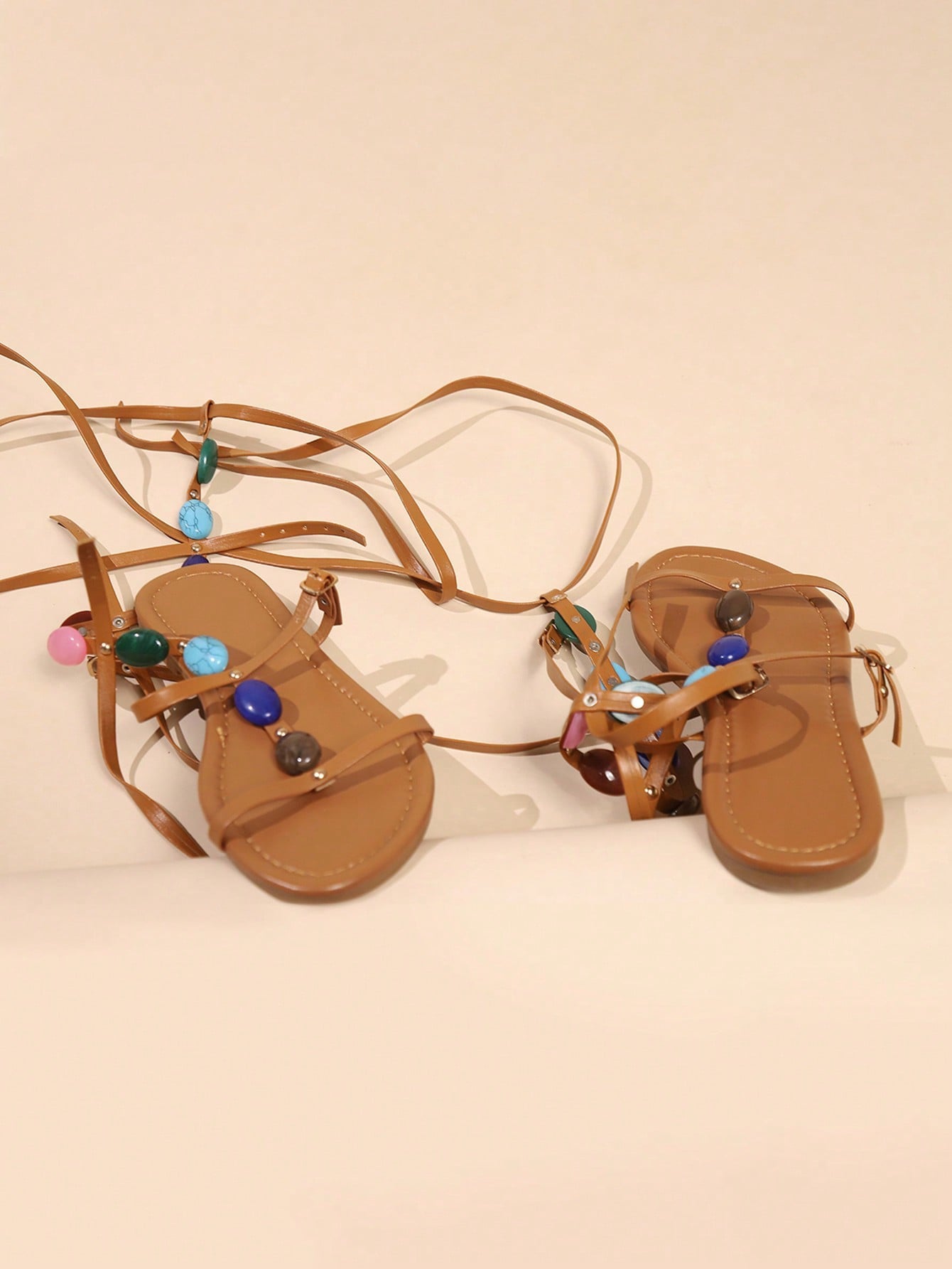 Women's open-toe flat gladiator sandals with beaded pearl embellishment and buckle-tie straps in a tropical vacation style.