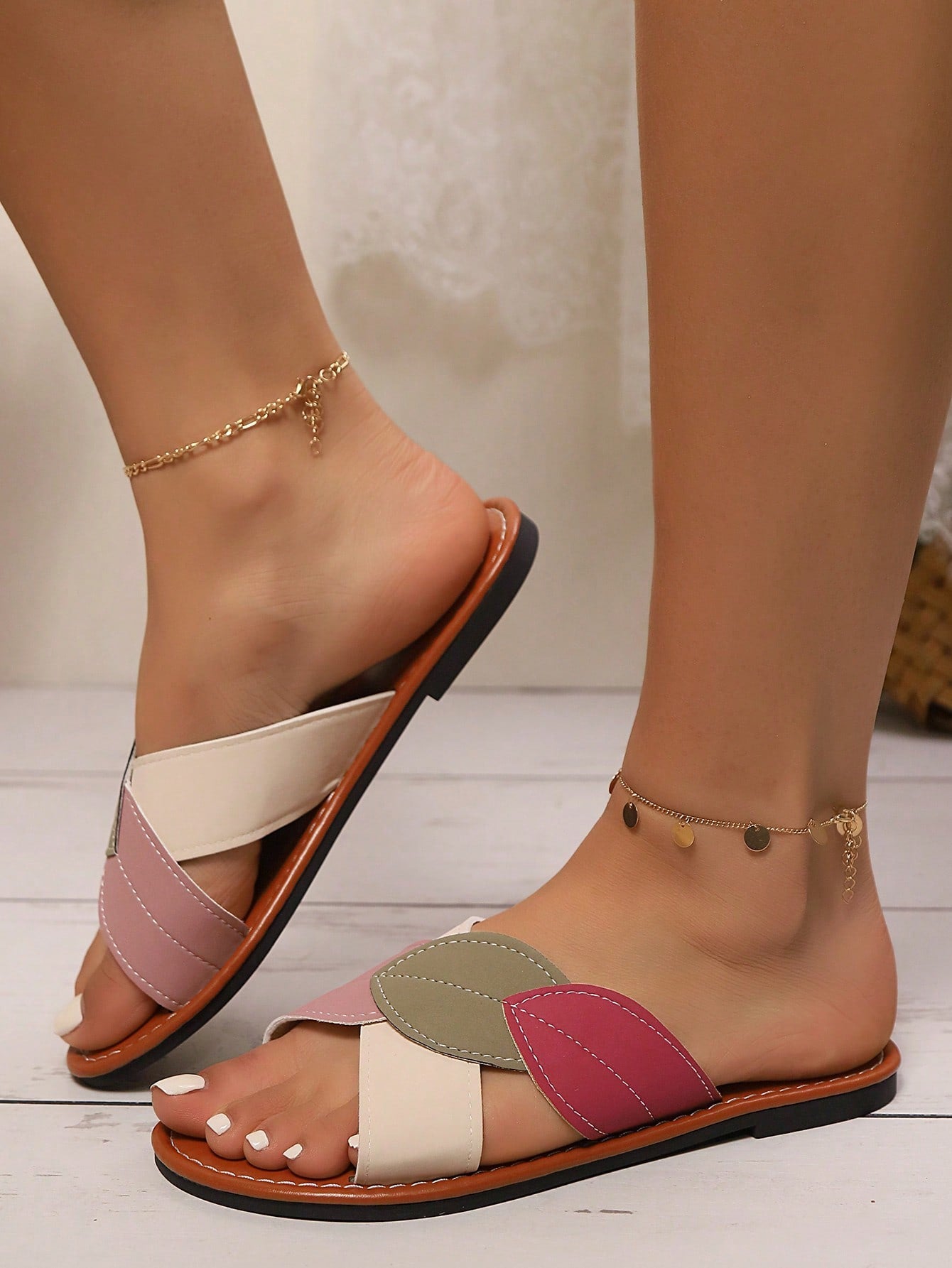 Women's beige flat slide sandals with criss-cross straps, open round toe, and leaf patchwork colorblock splicing detail.