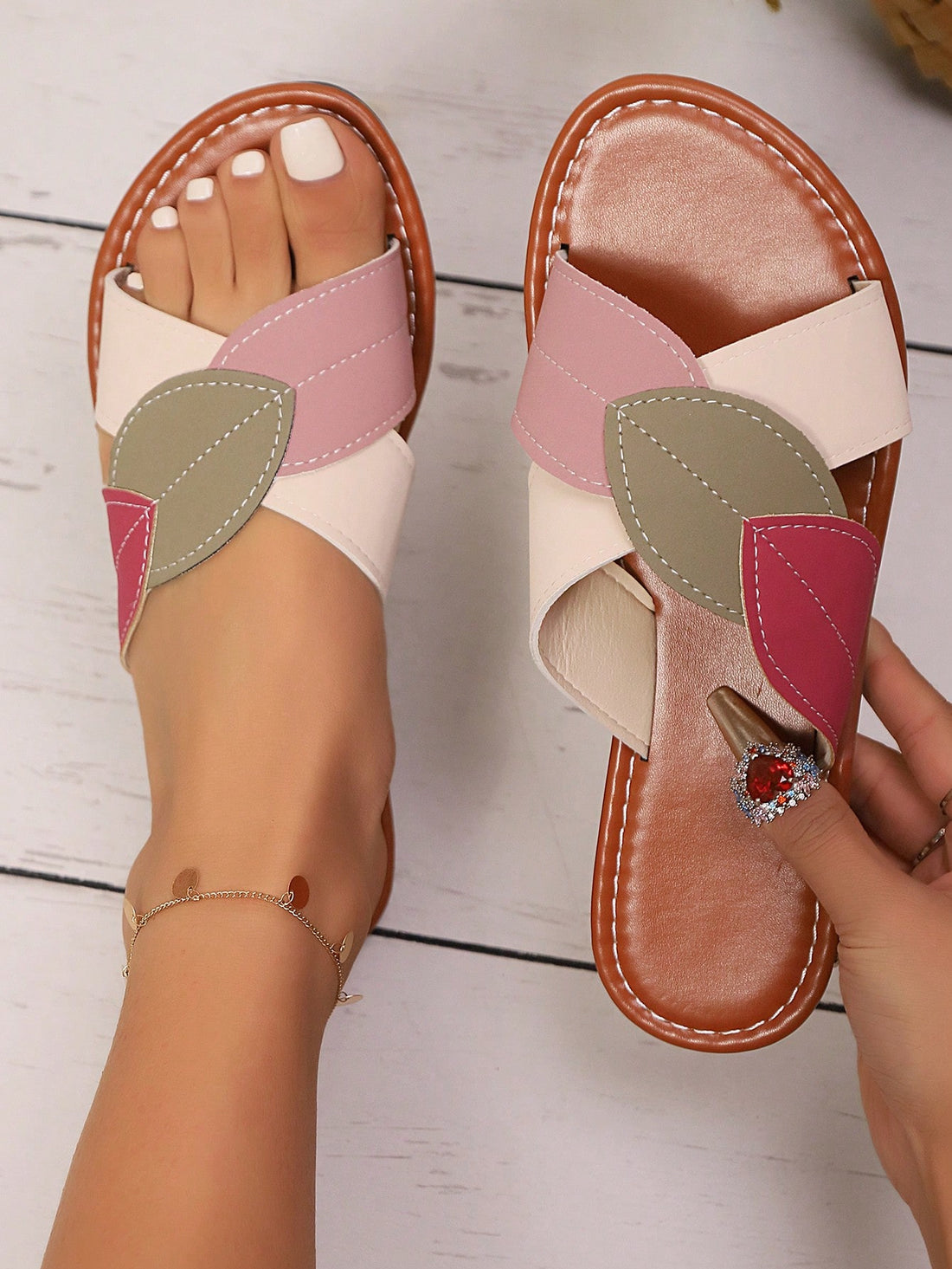 Women's beige flat slide sandals with criss-cross straps, open round toe, and leaf patchwork colorblock splicing detail.