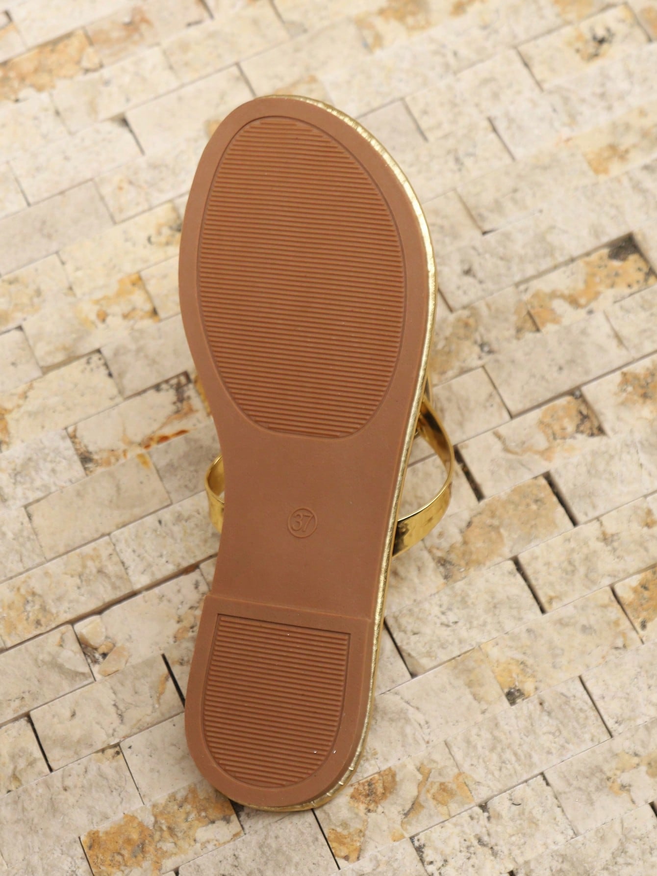 Women’s gold flat slide sandals with open toe post design and metal buckle detail, shown as fashionable outdoor summer footwear.