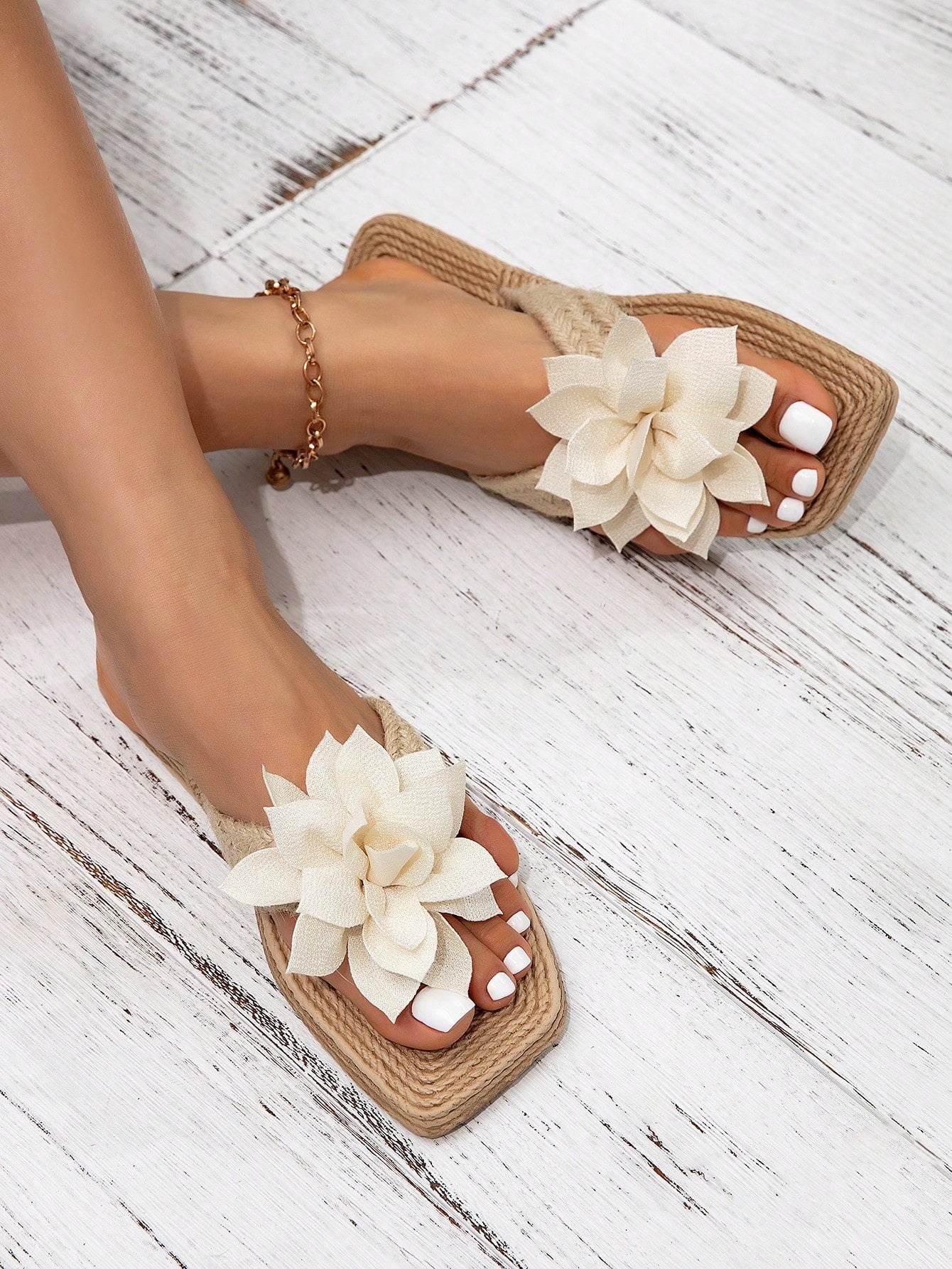 Women’s flat linen flip-flops with flower appliqué decor and sole, beach slipper style.