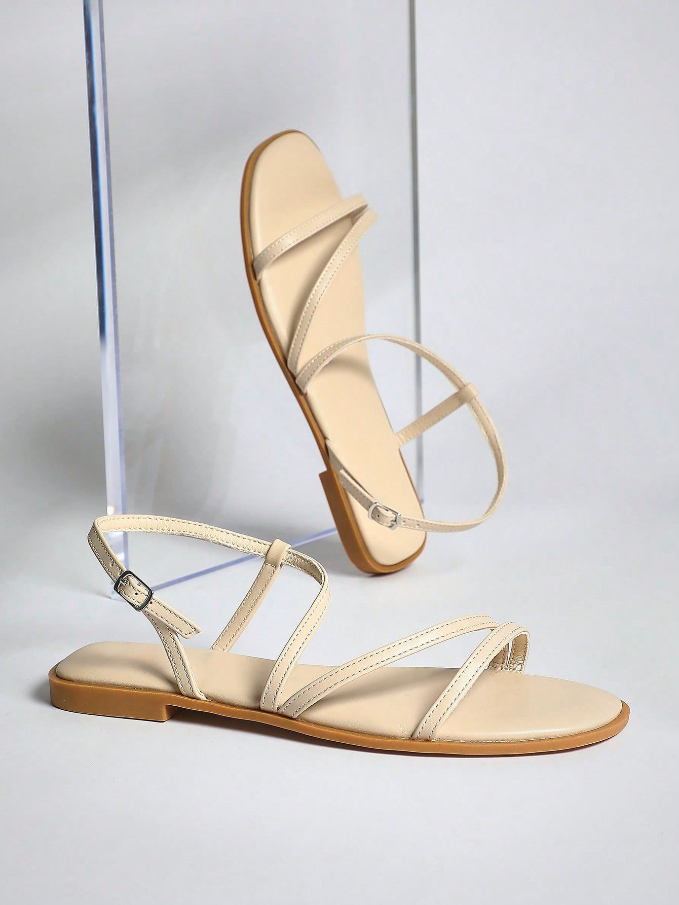 Women's flat open-toe sandals featuring a buckle detail and PU leather construction with a flat sole.