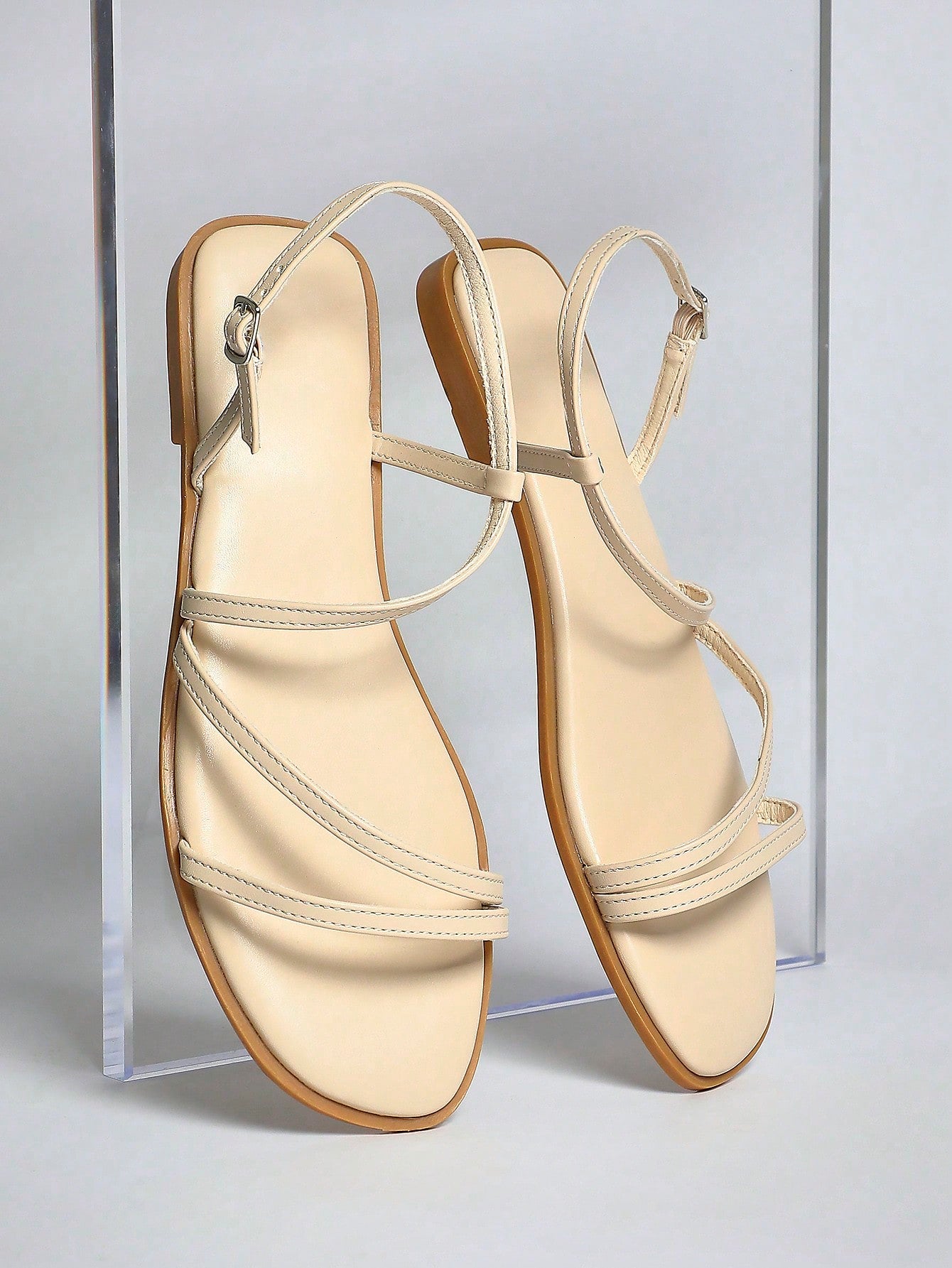 Women's flat open-toe sandals featuring a buckle detail and PU leather construction with a flat sole.