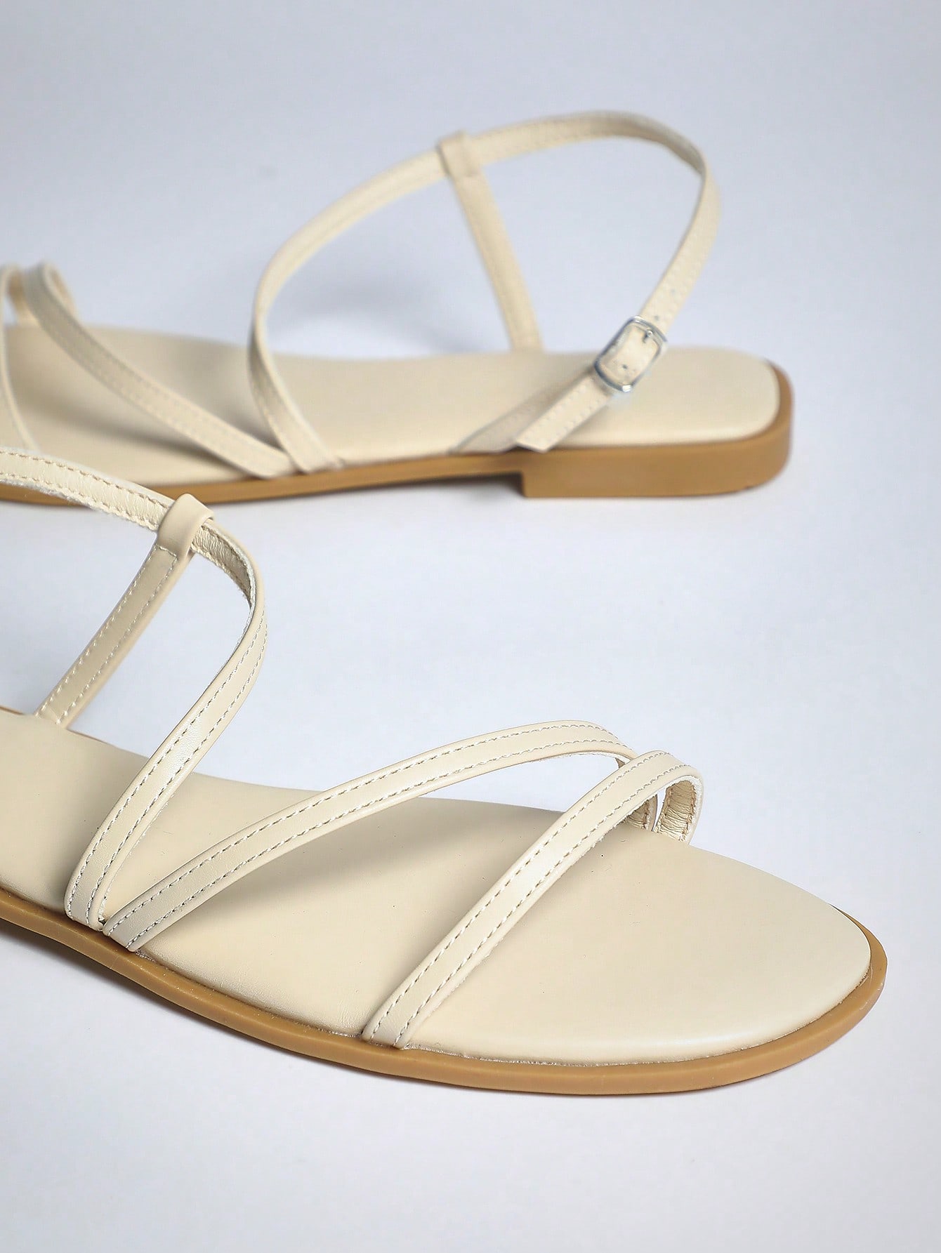 Women's flat open-toe sandals featuring a buckle detail and PU leather construction with a flat sole.