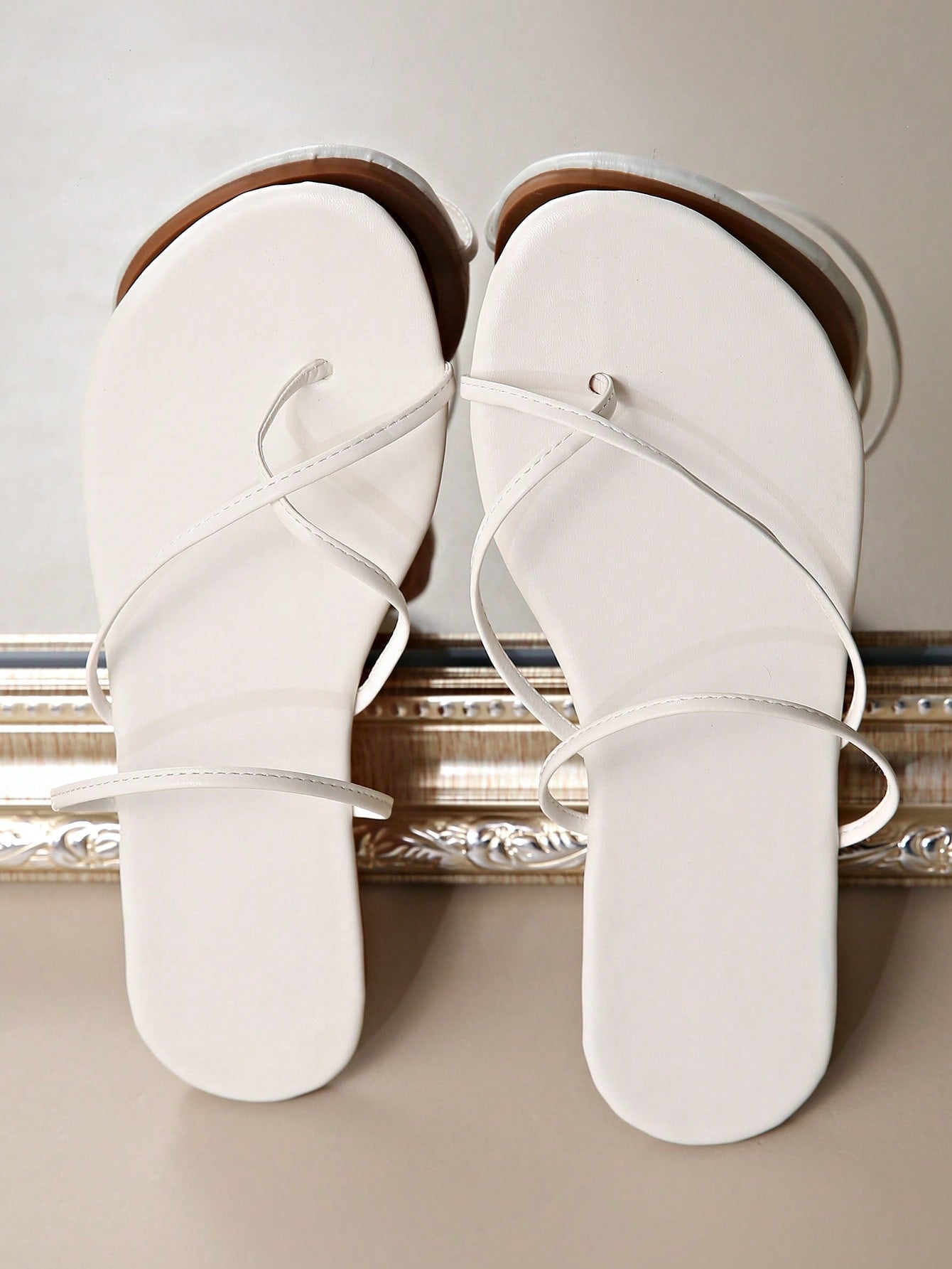 Women’s gold thong flat sandals with strappy asymmetrical design, suitable for outdoor and beach wear