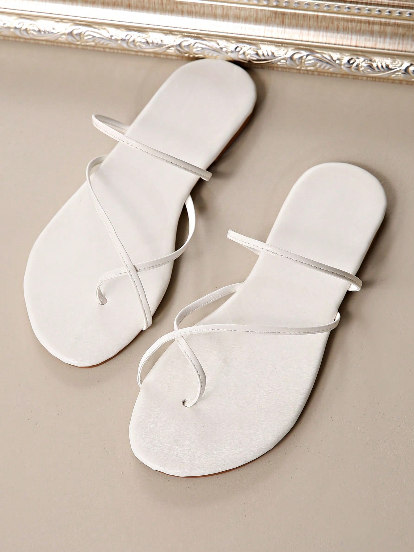 Women’s gold thong flat sandals with strappy asymmetrical design, suitable for outdoor and beach wear
