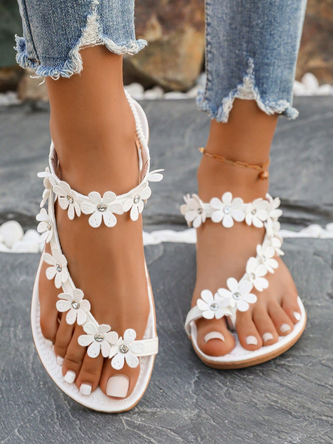 Women's white flat beach thong sandals with toe-post design, featuring flower applique and rhinestone embellishment on the upper, casual summer slide style.