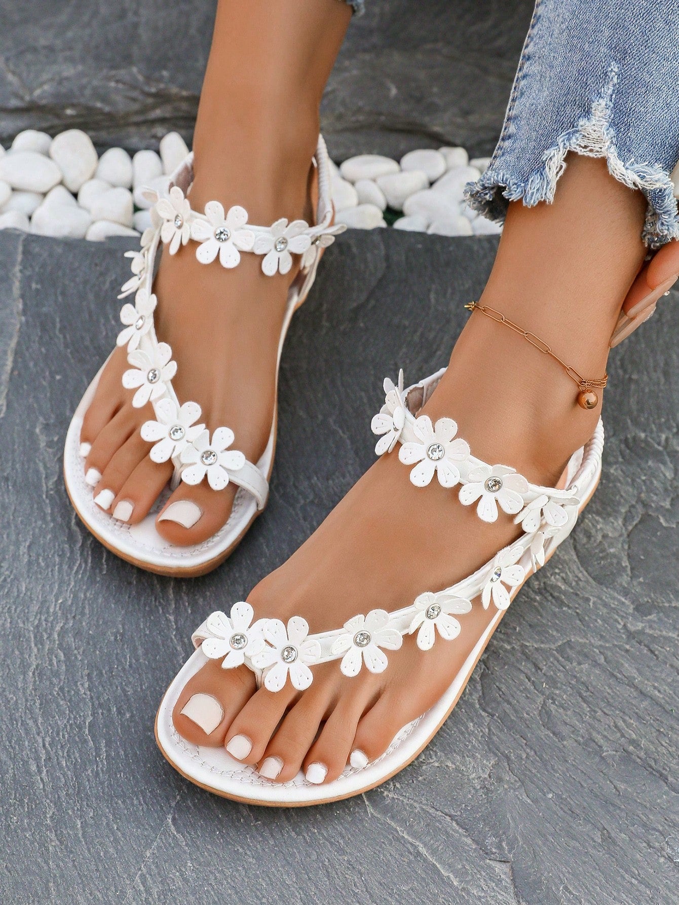 Women's white flat beach thong sandals with toe-post design, featuring flower applique and rhinestone embellishment on the upper, casual summer slide style.
