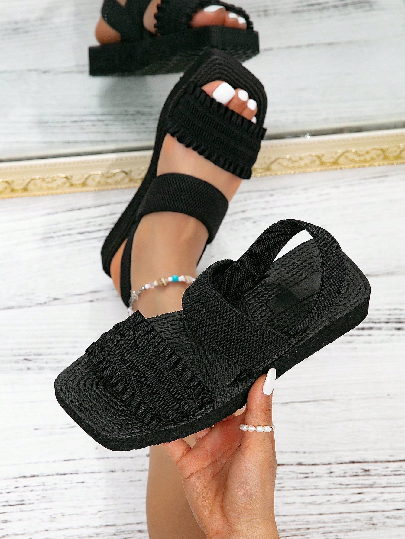 Women's black flat gladiator sandals with ruched and ruffle trim, textured fabric upper, and open-toe design for party, outdoor, and casual wear.