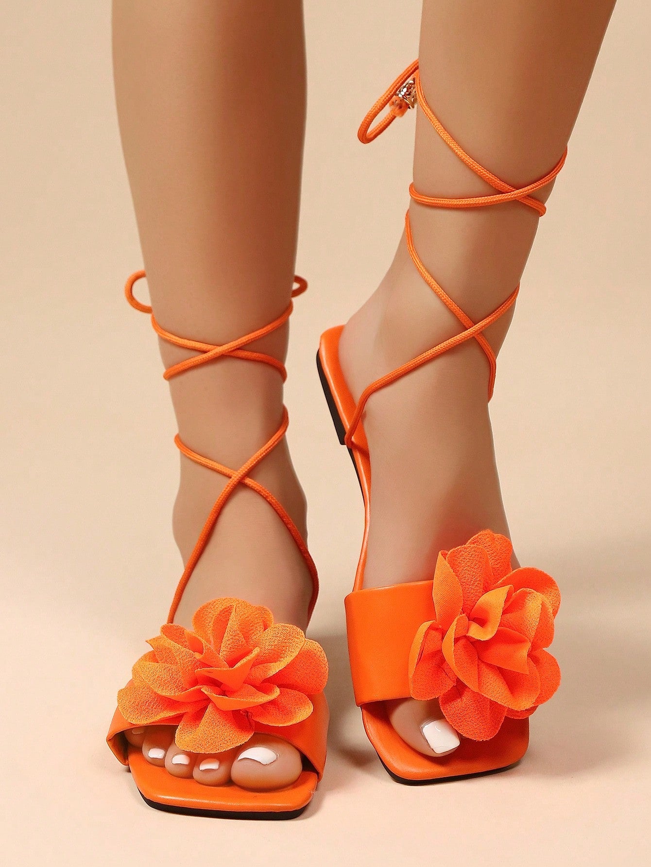 Women's flat strappy sandals with bow detail, open toe, and Roman-style criss-cross lace-up design in an elegant look.