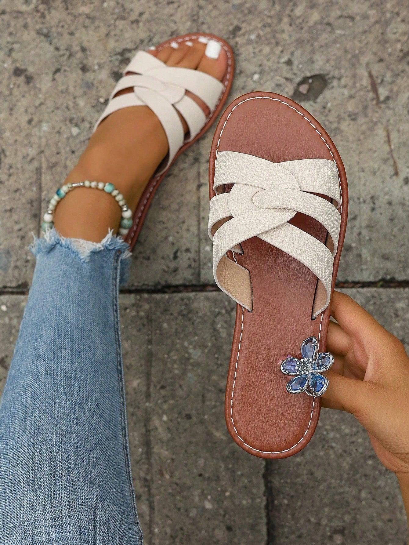 Pair of women’s open-toe flat slide sandals with an H-shaped strap, braided and embossed details, and a minimalist slip-on design suitable for casual outdoor wear.