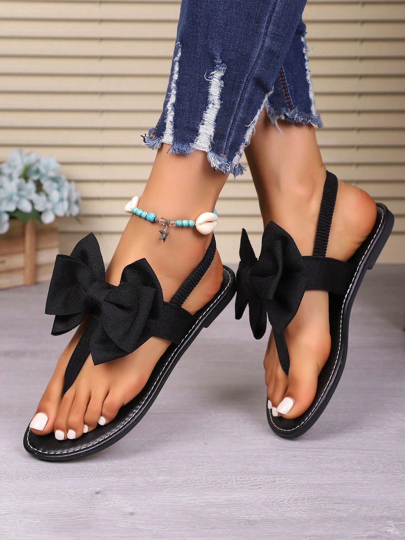 Pair of women’s solid color bohemian flat sandals with fabric bow detail, toe post thong design, and slide-on style for casual beach, outdoor, vacation, and home wear.