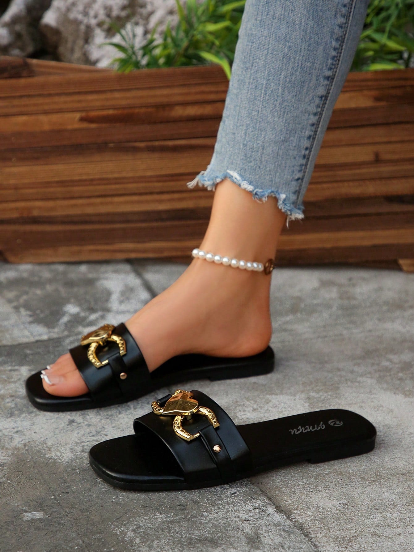 Women's black open-toe slide sandals featuring a 3D heart buckle detail and flat sole, suitable for casual indoor and outdoor summer wear.