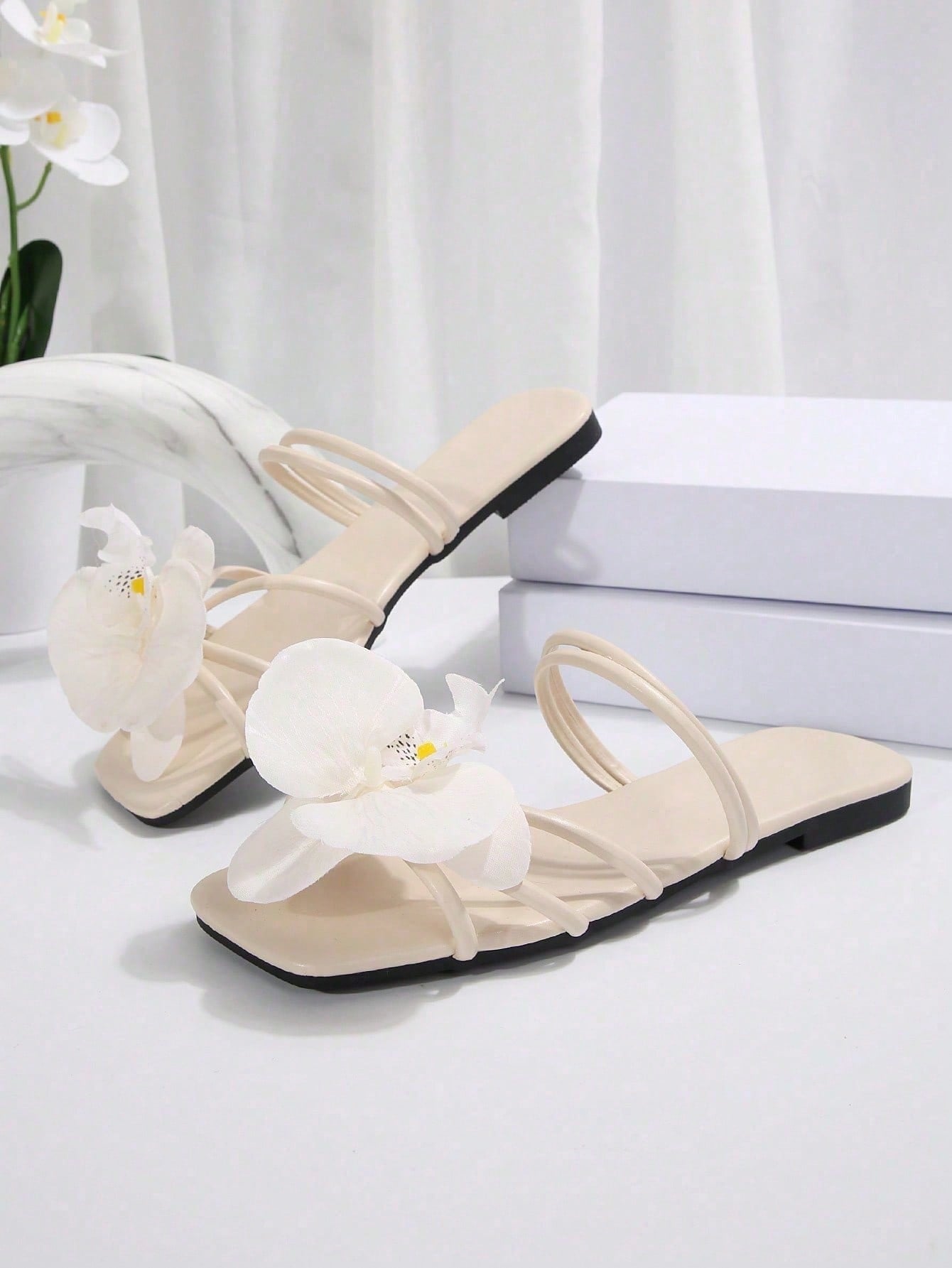 Women's flat slide sandals with open toe, floral applique detail, and criss-cross straps, shown as casual vacation-style summer footwear.