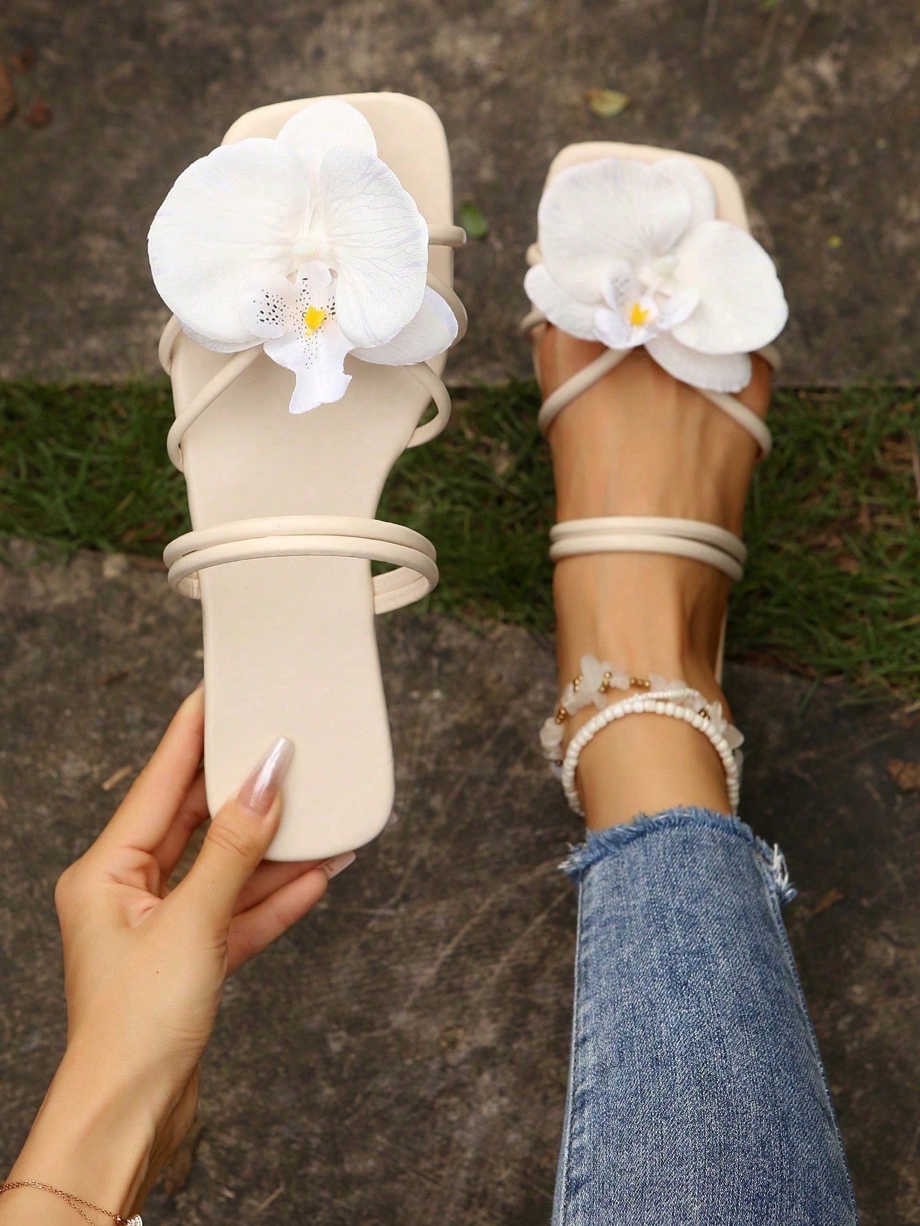 Women's flat slide sandals with open toe, floral applique detail, and criss-cross straps, shown as casual vacation-style summer footwear.