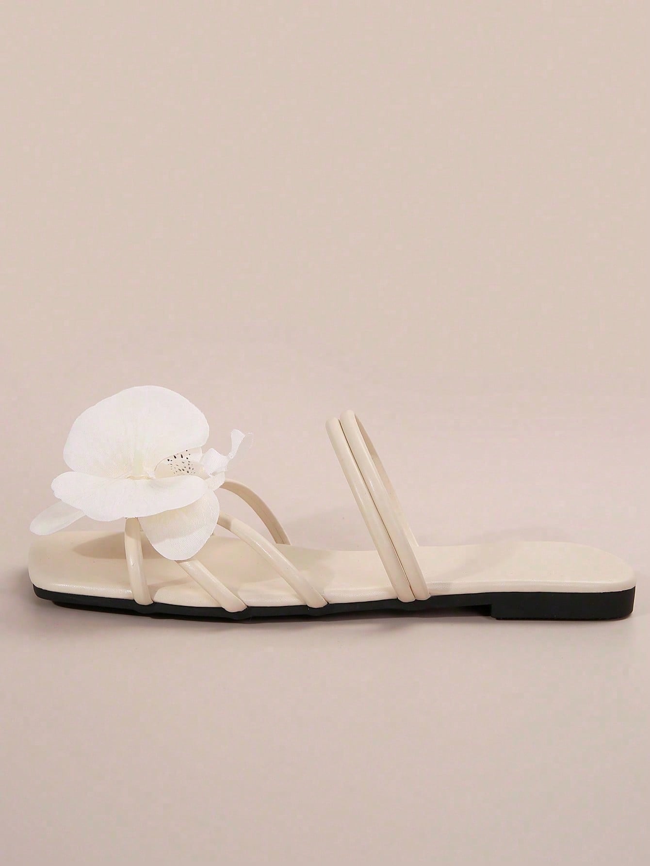 Women's flat slide sandals with open toe, floral applique detail, and criss-cross straps, shown as casual vacation-style summer footwear.